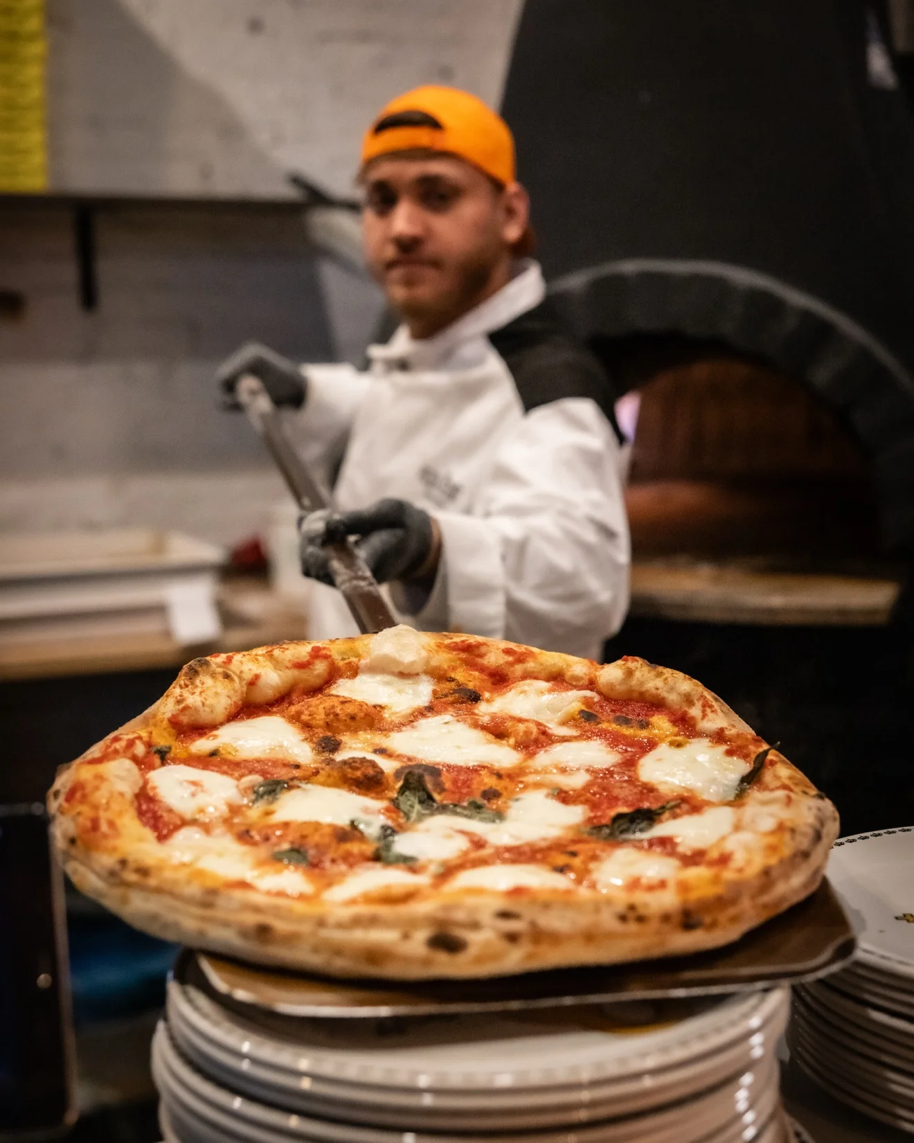 Chef grating parmesan over a pizza at Pizza Secret