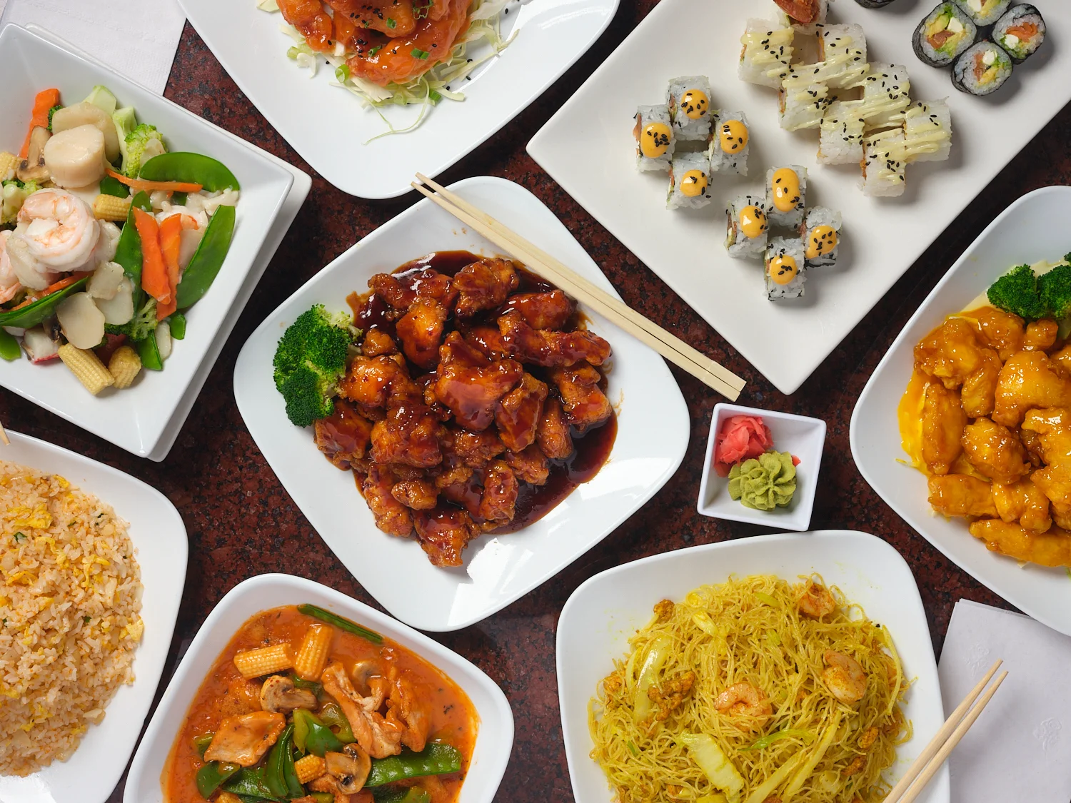 Assorted Chinese dishes including sweet and sour chicken and sushi rolls