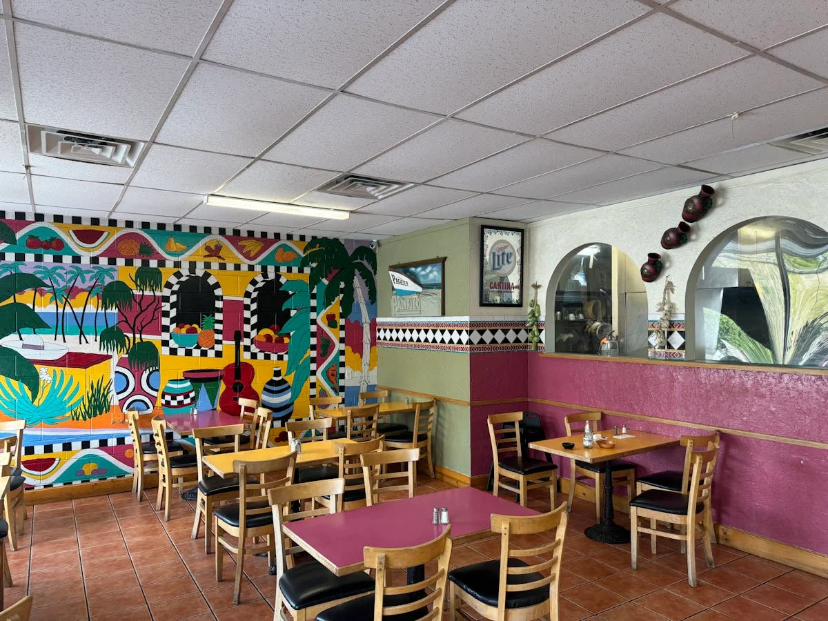 Colorful restaurant interior with vibrant mural and wooden tables