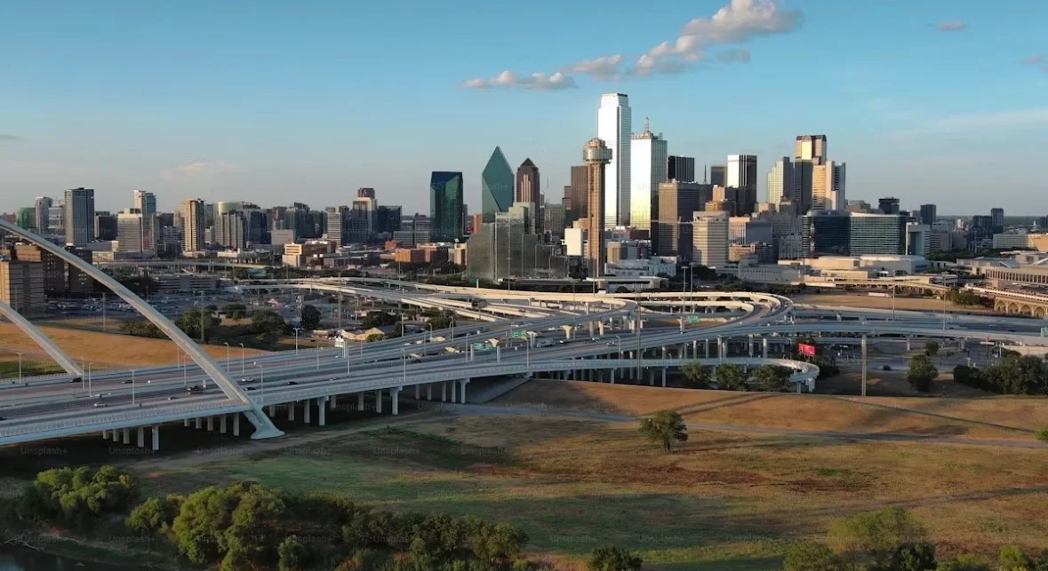 Aerial view of a city skyline with highways and green spaces.