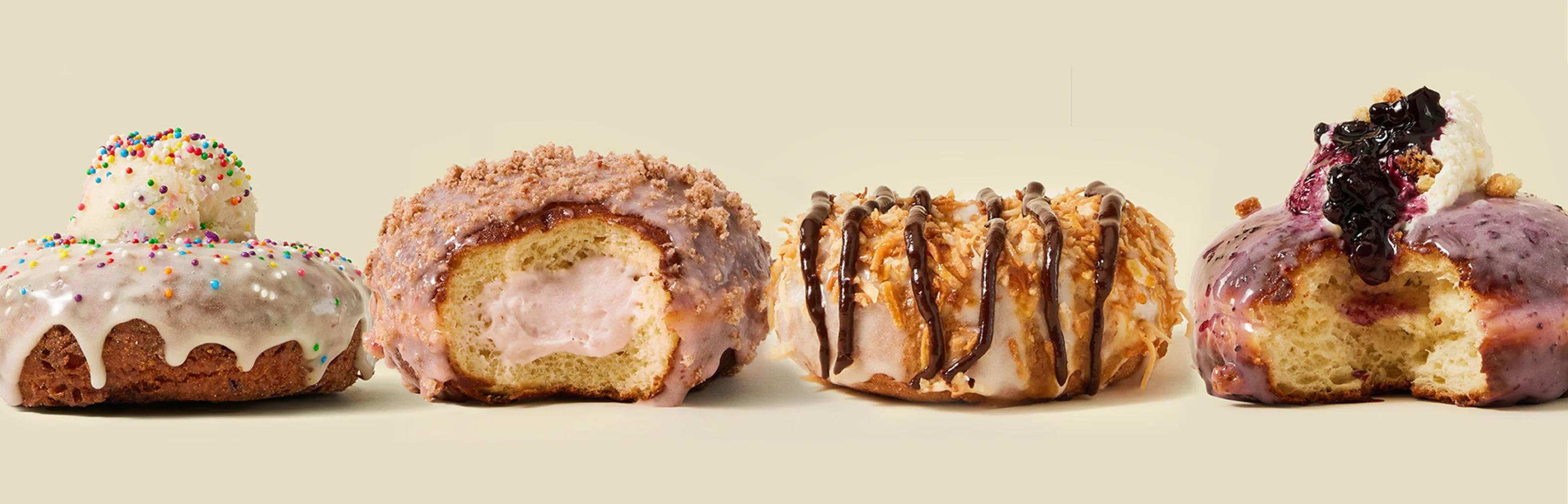 Four colorful donuts with various toppings and fillings on a light background.