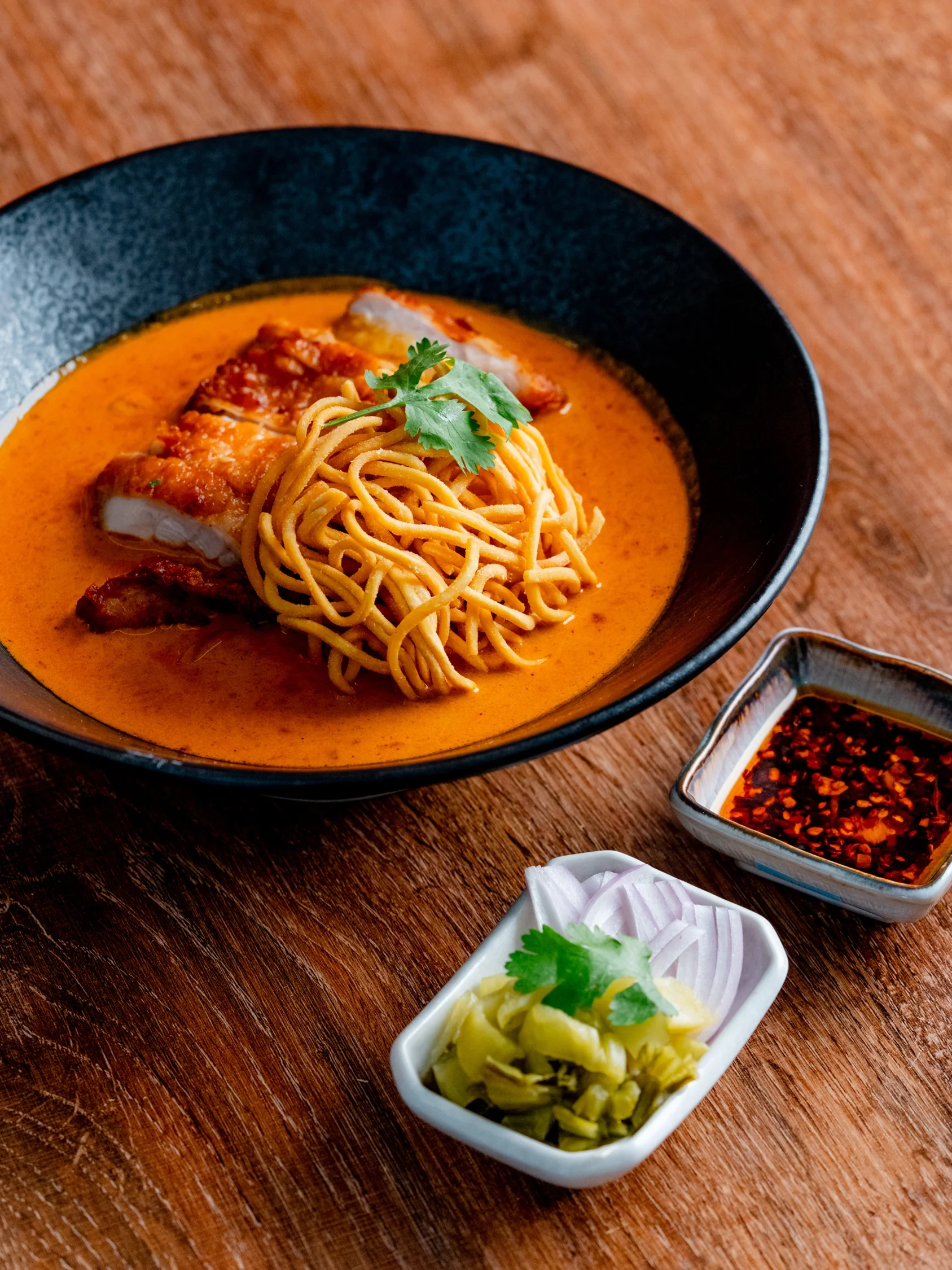 Bowl of Thai red curry noodles with crispy pork