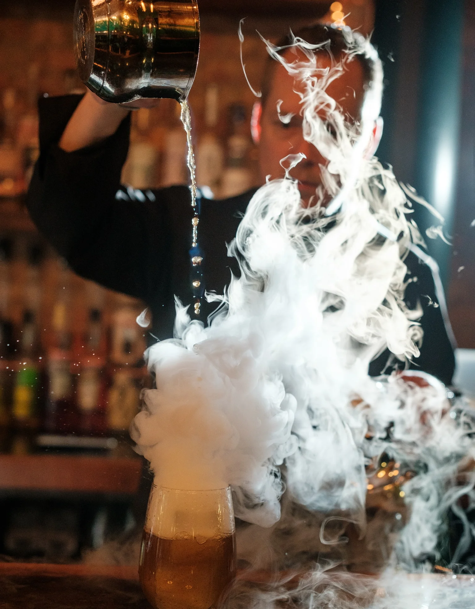 Bartender pouring a smoky cocktail at a stylish bar