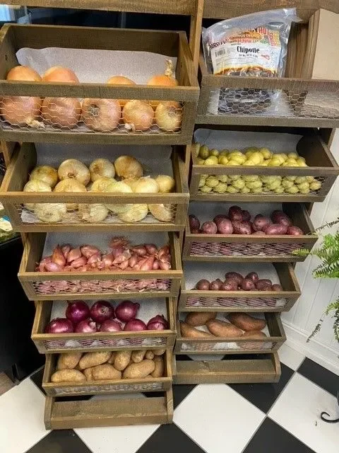 Variety of fresh onions and potatoes in wooden display racks