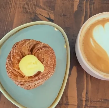 Golden Danish pastry with latte art on a rustic wooden table