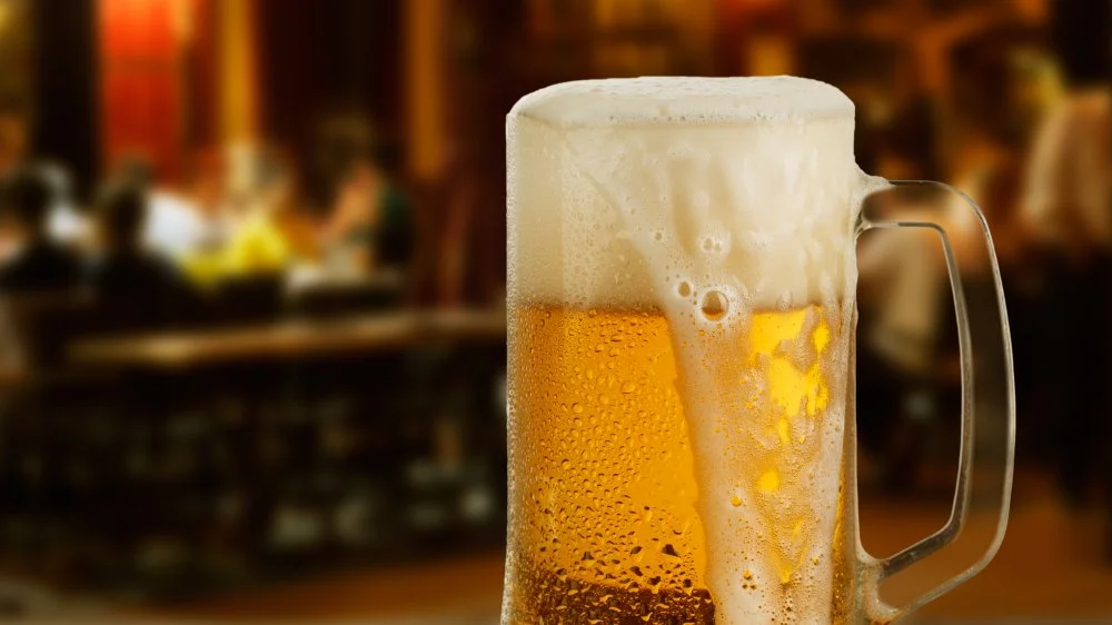 A selection of draft beers in glasses on a wooden bar top.