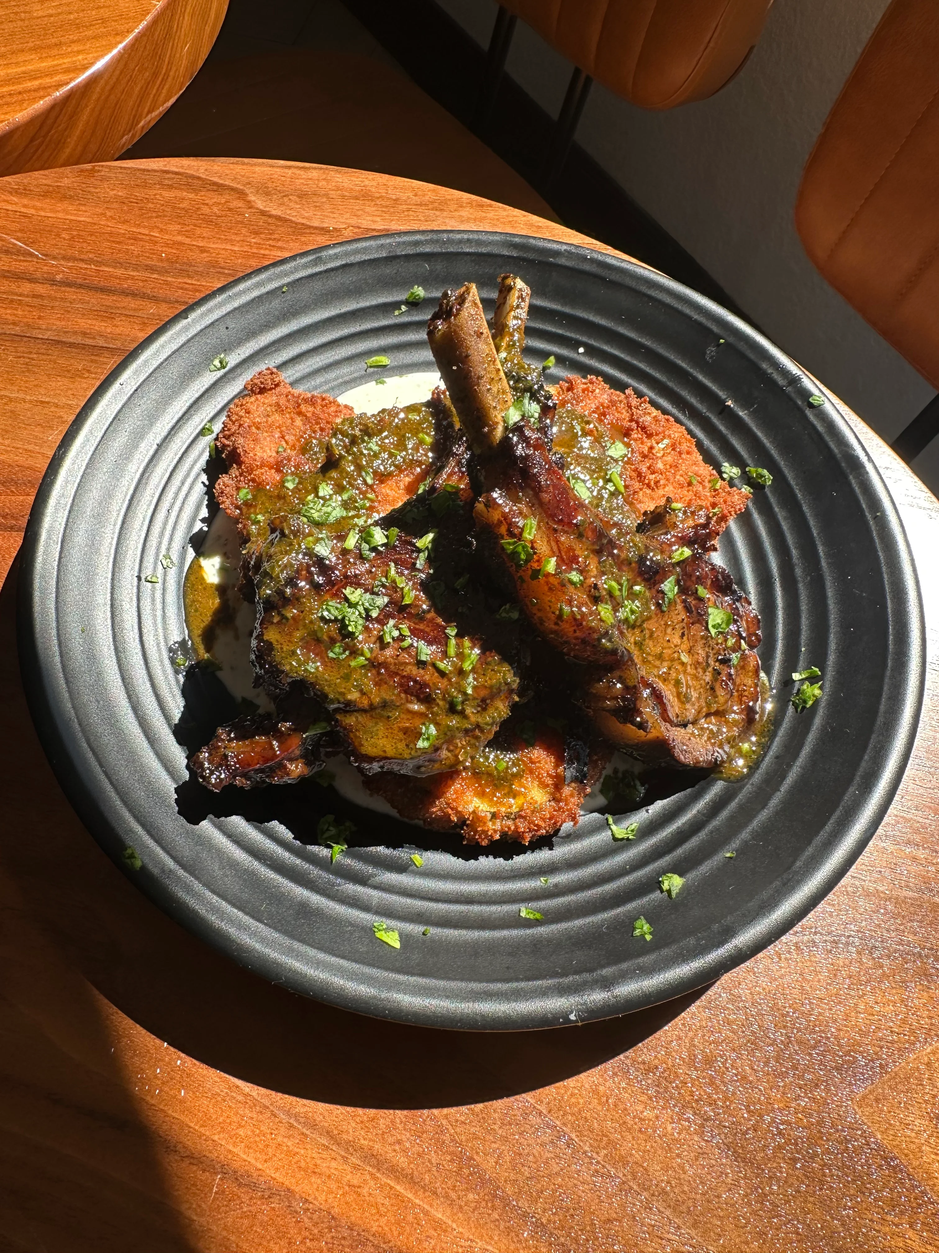 Grilled lamb chops with herb sauce on a black plate