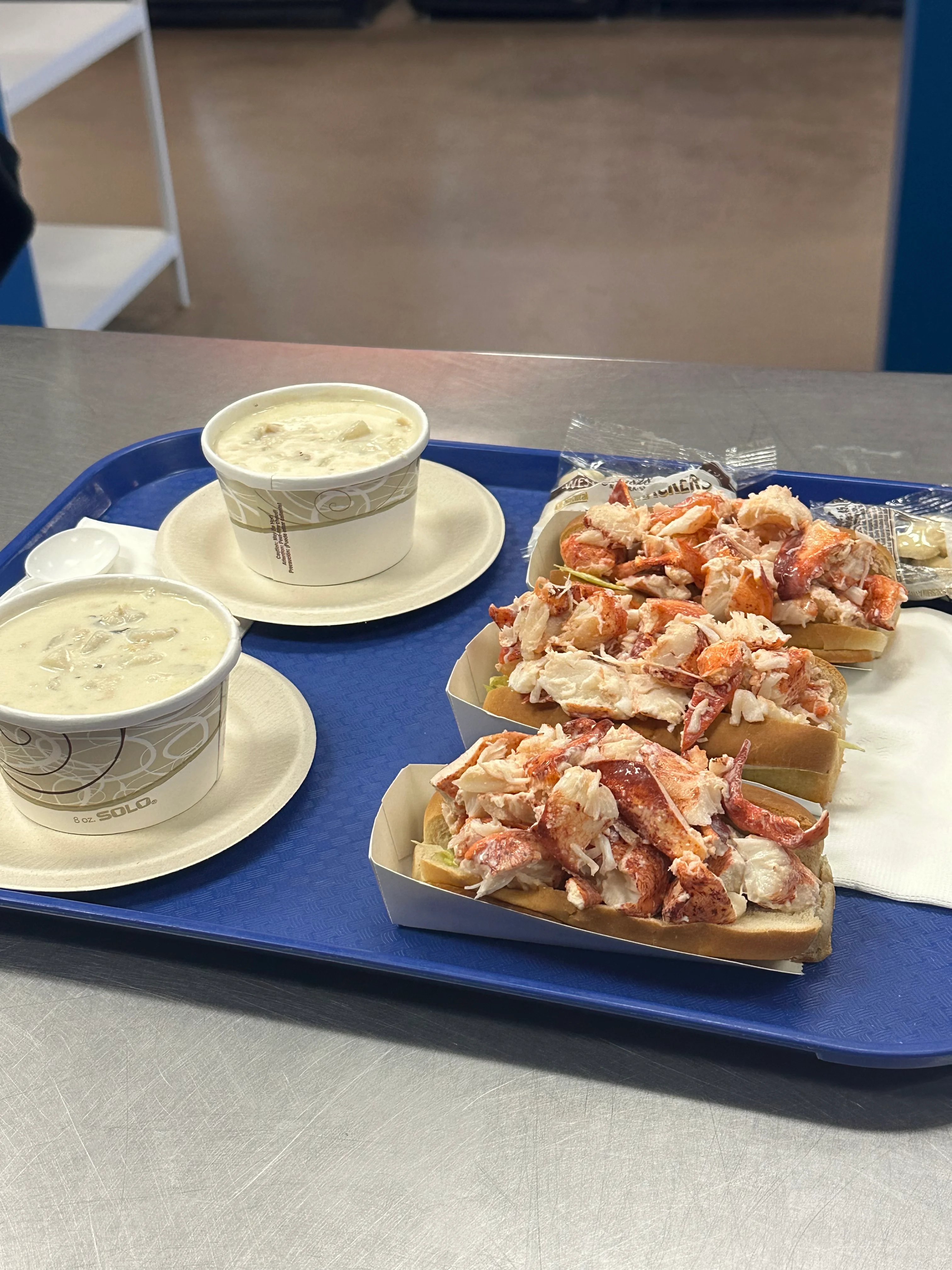 A tray filled with freshly made lobster rolls, each filled with chunks of lobster meat in soft bread rolls.