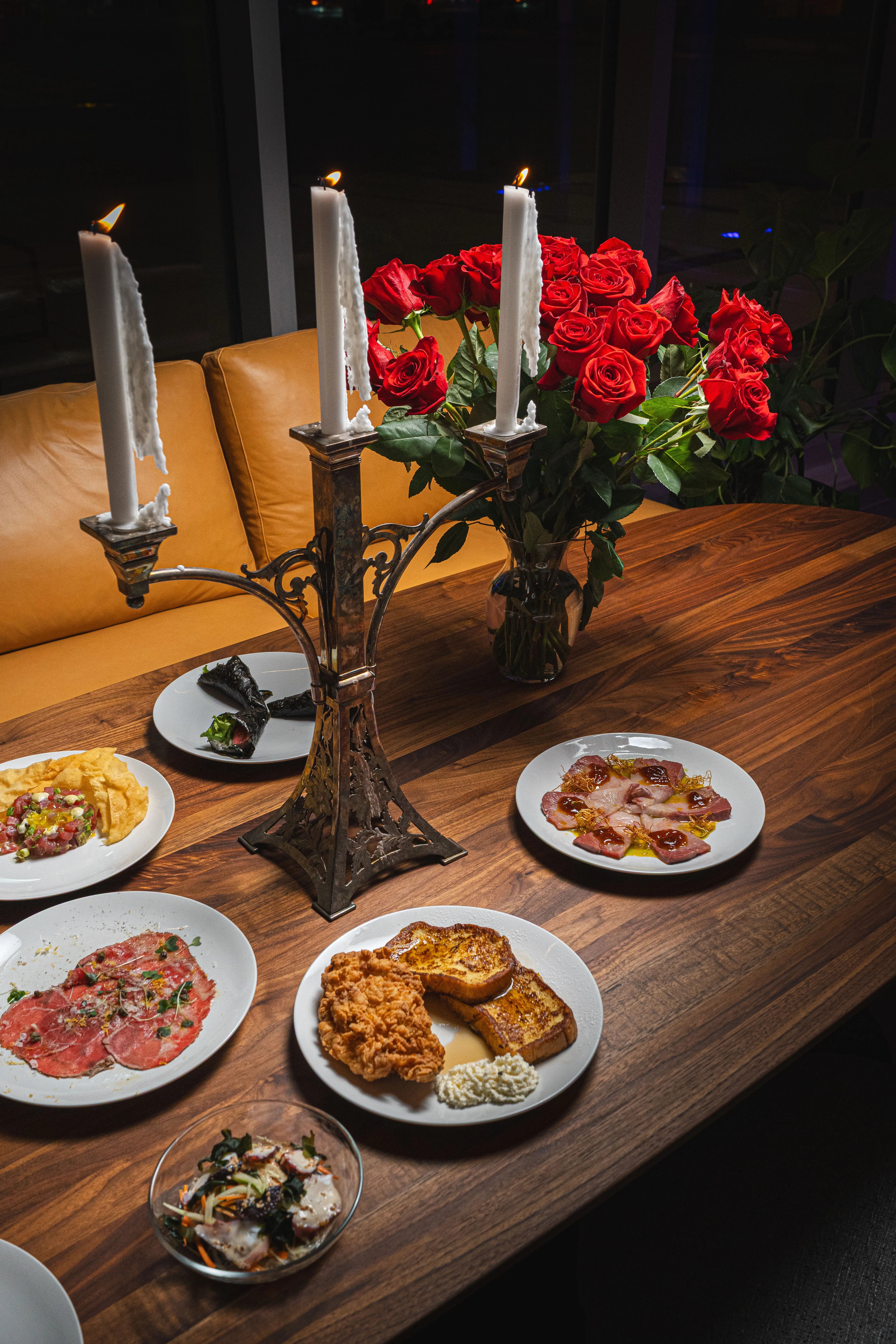 Elegant dining setup with assorted gourmet dishes and red roses