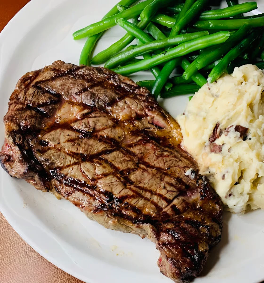 Grilled ribeye steak with green beans and mashed potatoes