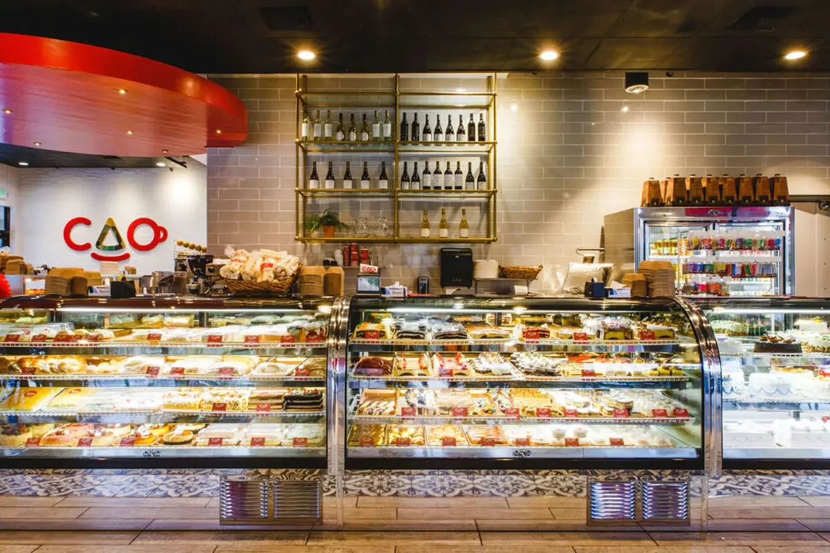 Modern café interior with pastry display and wine shelf