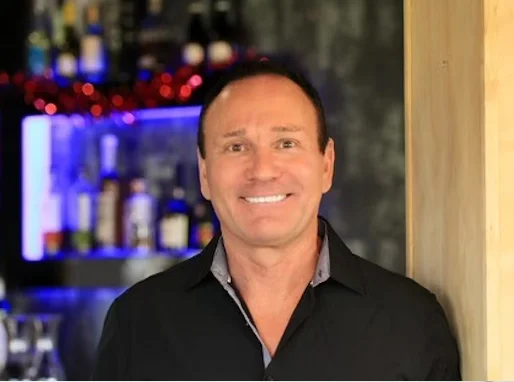 Bartender smiling at a modern bar counter with drinks in the background