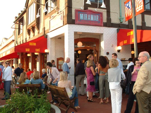 Busy restaurant entrance with outdoor seating and vibrant signage