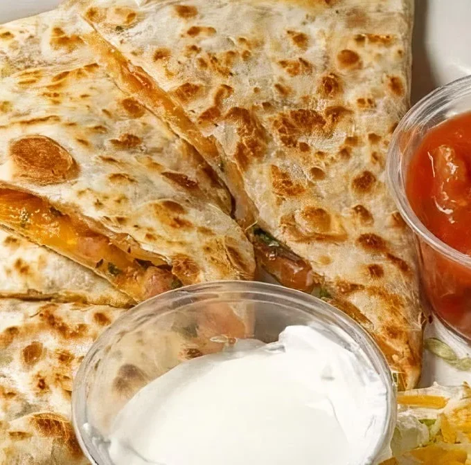 Cheesy quesadilla served with salsa and sour cream