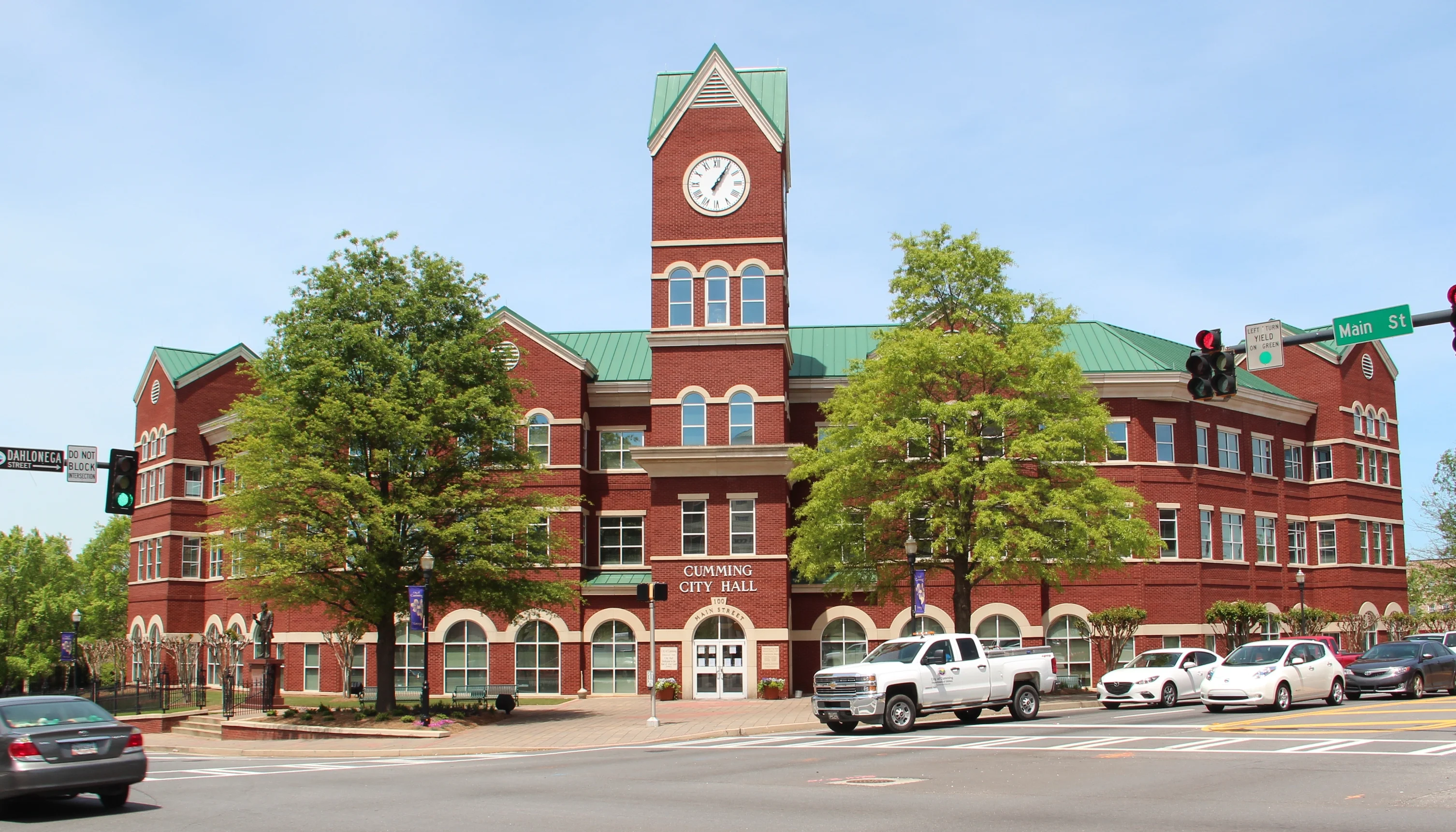 Cumming City Hall building with clock tower and green roof.
