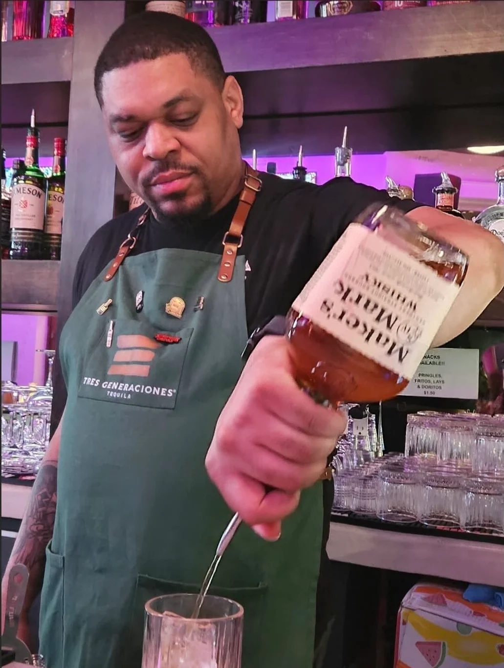 Bartender pouring whiskey into a glass at a vibrant bar