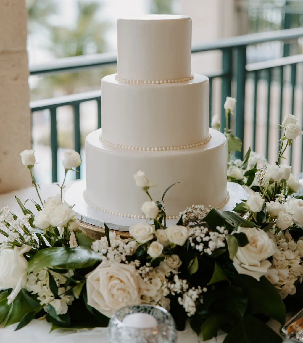 Elegant three-tier wedding cake adorned with white roses