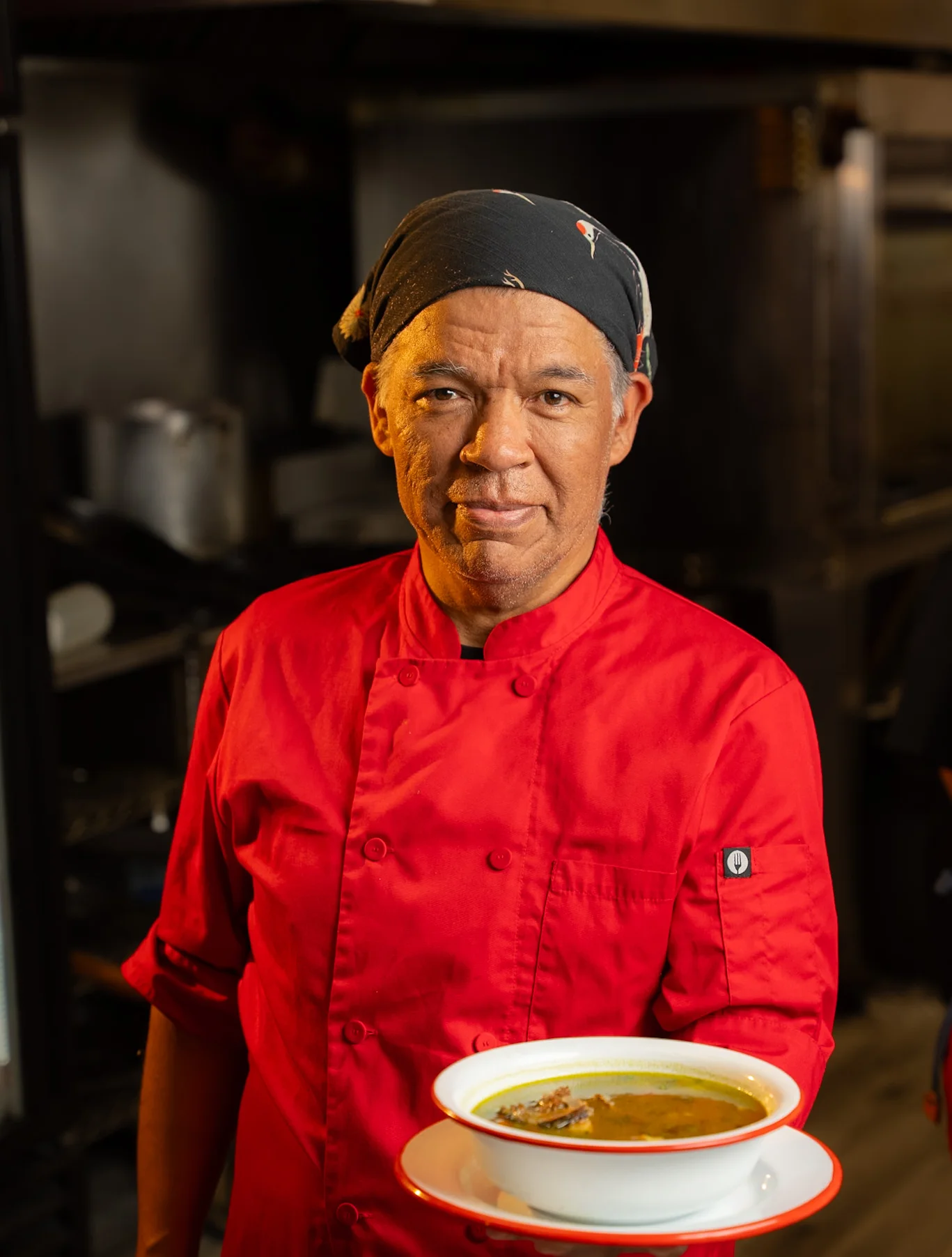 Chef presenting a bowl of traditional Mexican pozole