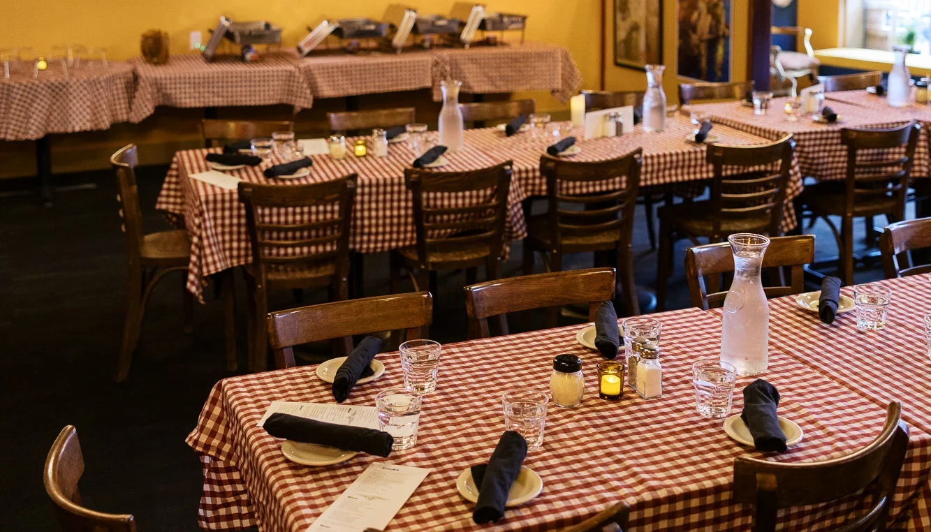 Cozy restaurant interior with checkered tablecloths and warm lighting.
