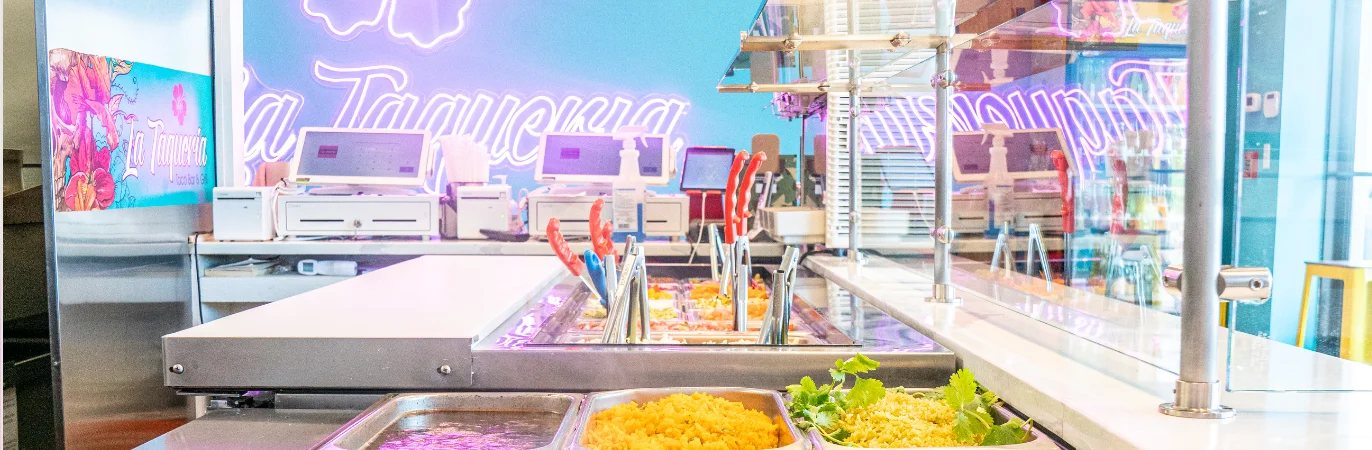 Colorful taqueria counter with fresh toppings and vibrant decor