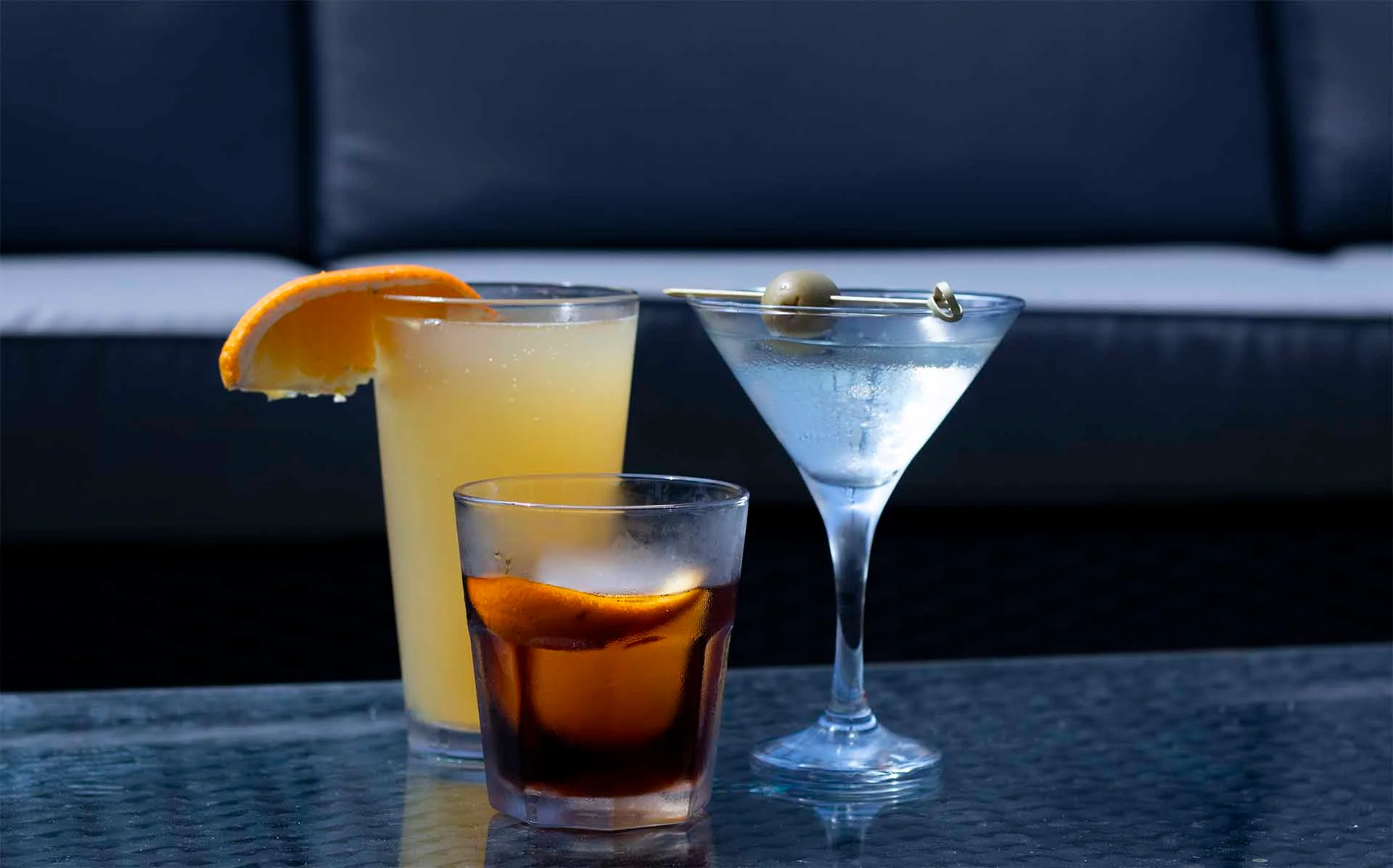 Three stylish cocktails on a glass table