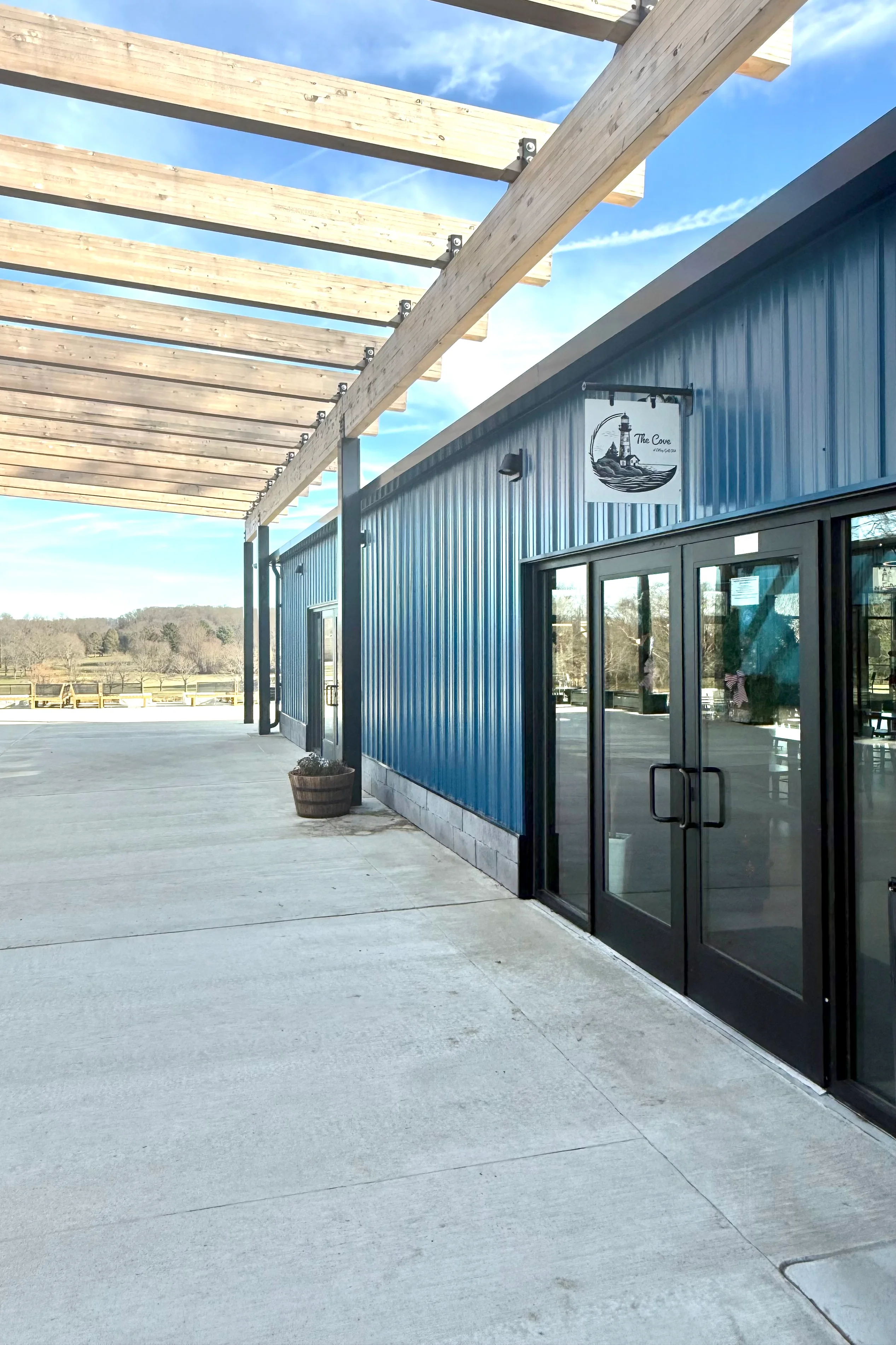 Modern restaurant exterior with wooden pergola and blue metal siding