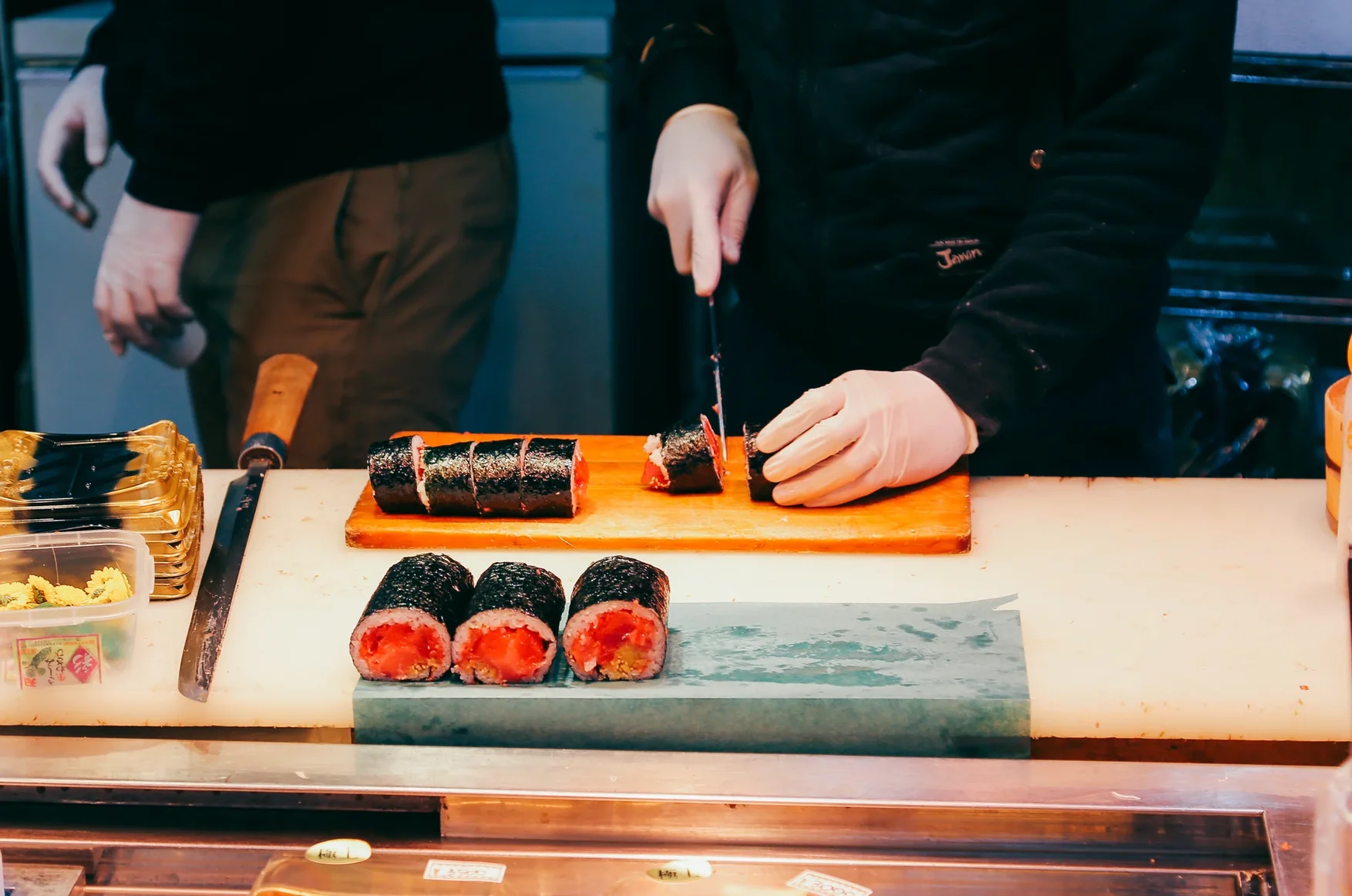 Japanese sushi rolls being sliced by a chef