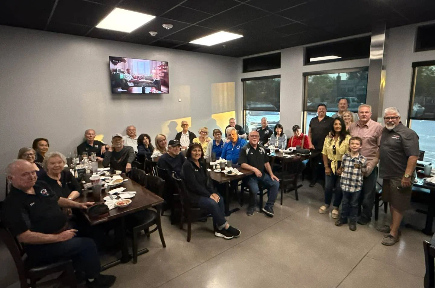 A group gathering at a dining establishment with people seated around tables, enjoying their time together in a cozy interior setting.