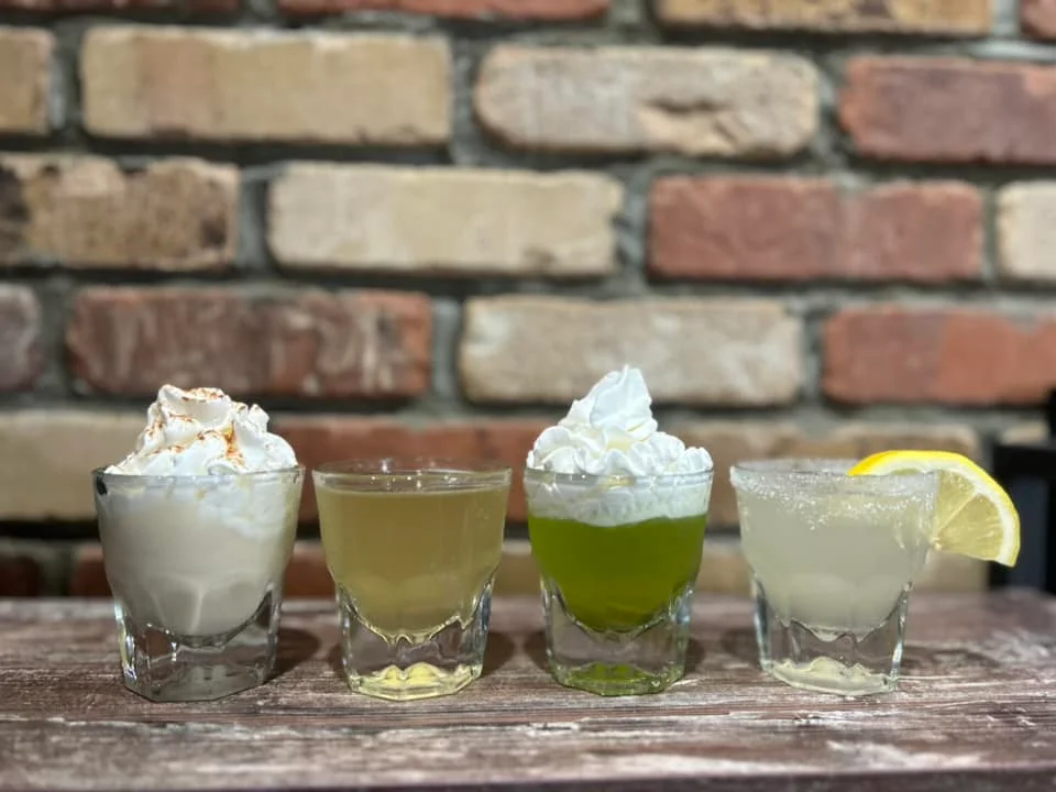 Colorful cocktails with whipped cream on a rustic wooden table