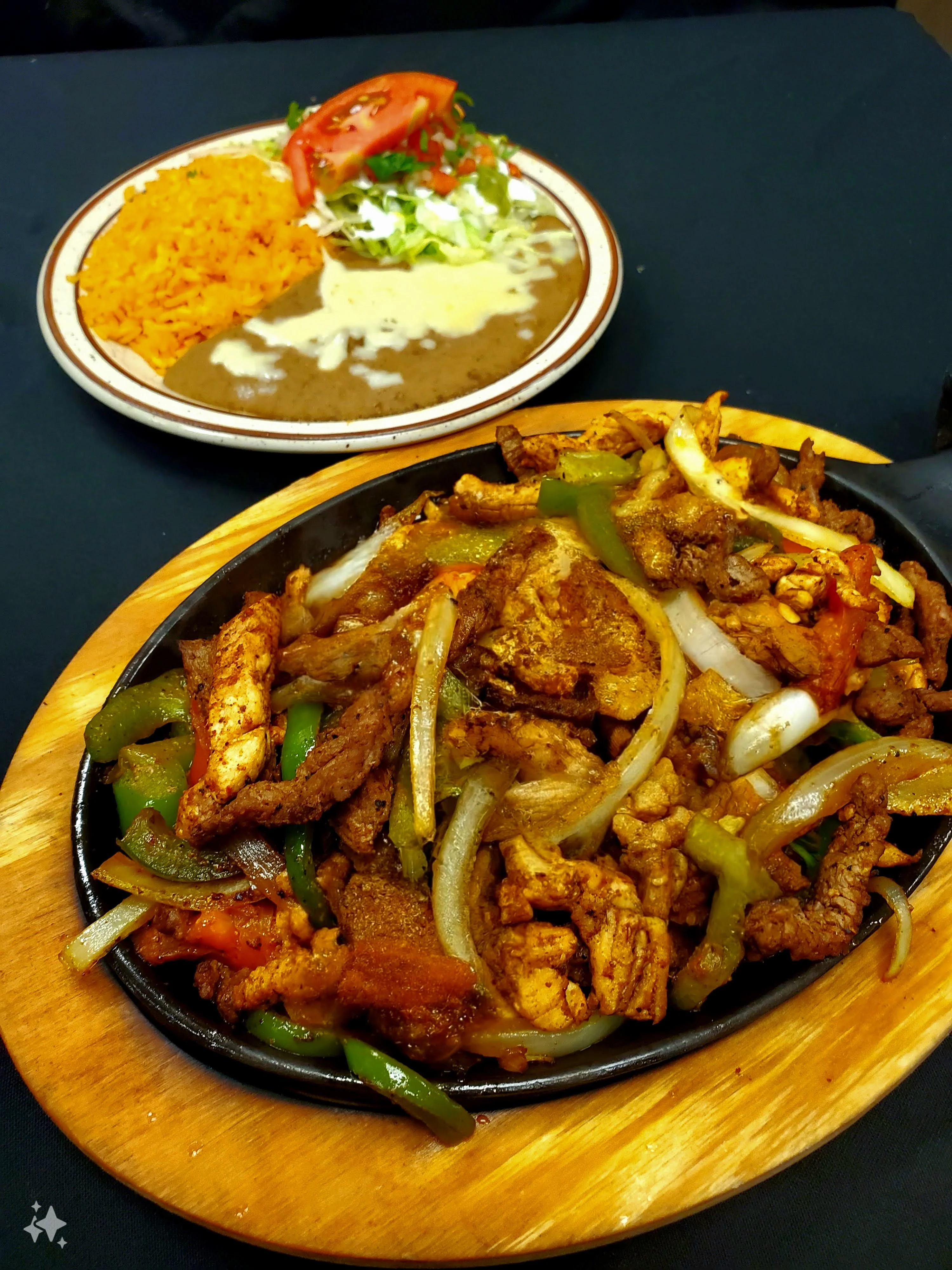 A sizzling plate of Mixed Fajitas with tender grilled chicken and juicy steak strips, onions, tomatoes, and green peppers, all perfectly seasoned and served hot. The best fajita in Radford.