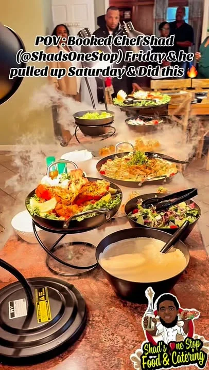 A buffet display featuring a variety of dishes being served at a gathering, with guests in the background.