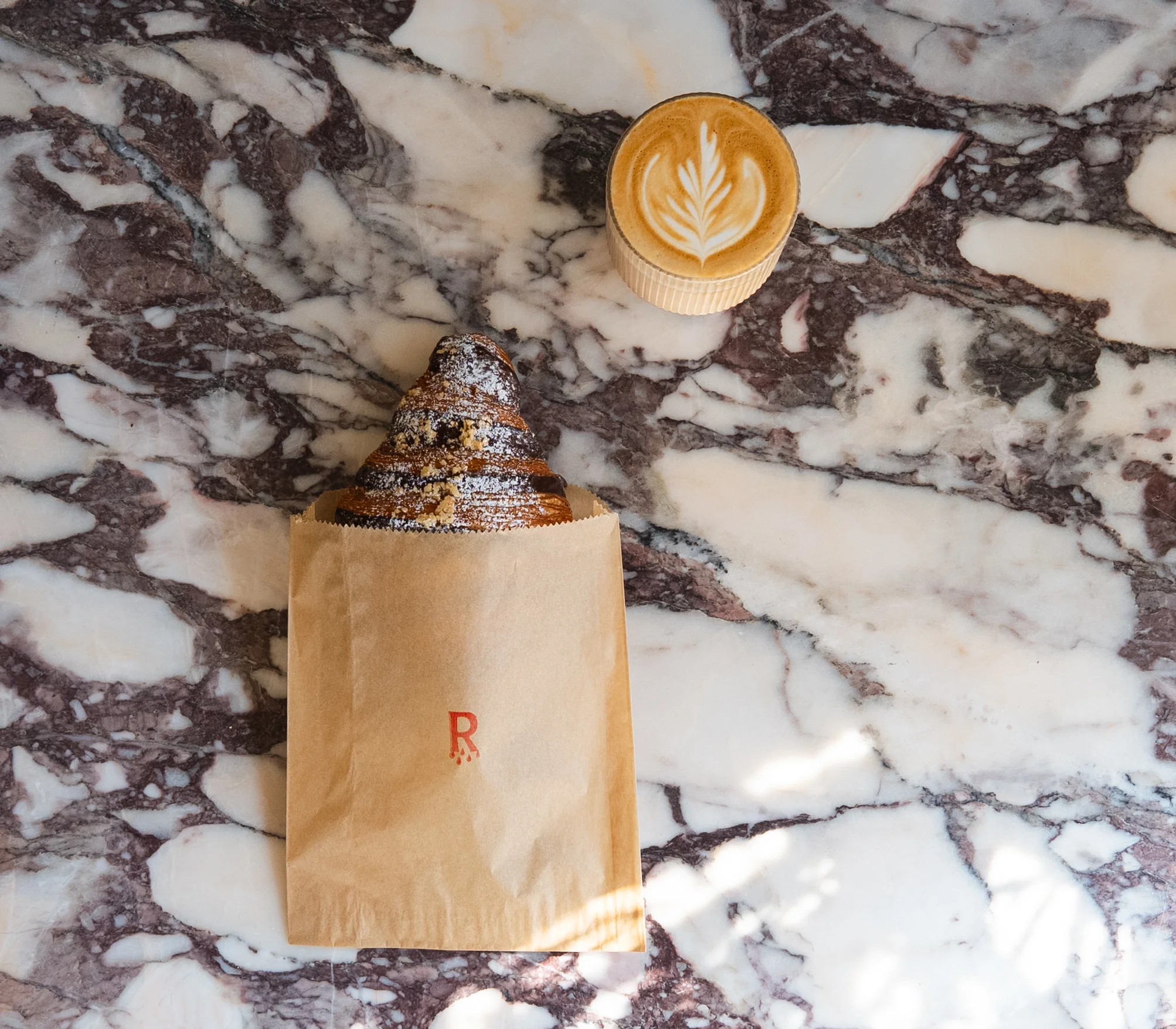 Nutella croissant with flat white on marble countertop 