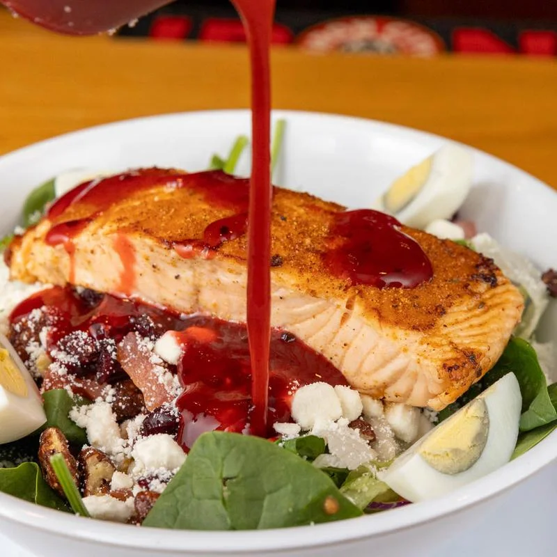 A fresh salmon salad with greens and colorful vegetables.