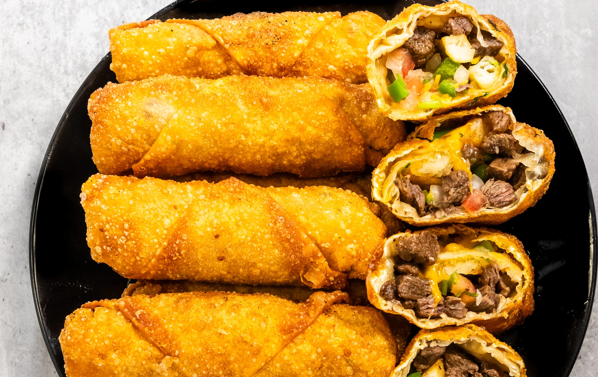 Crispy beef spring rolls on a black plate