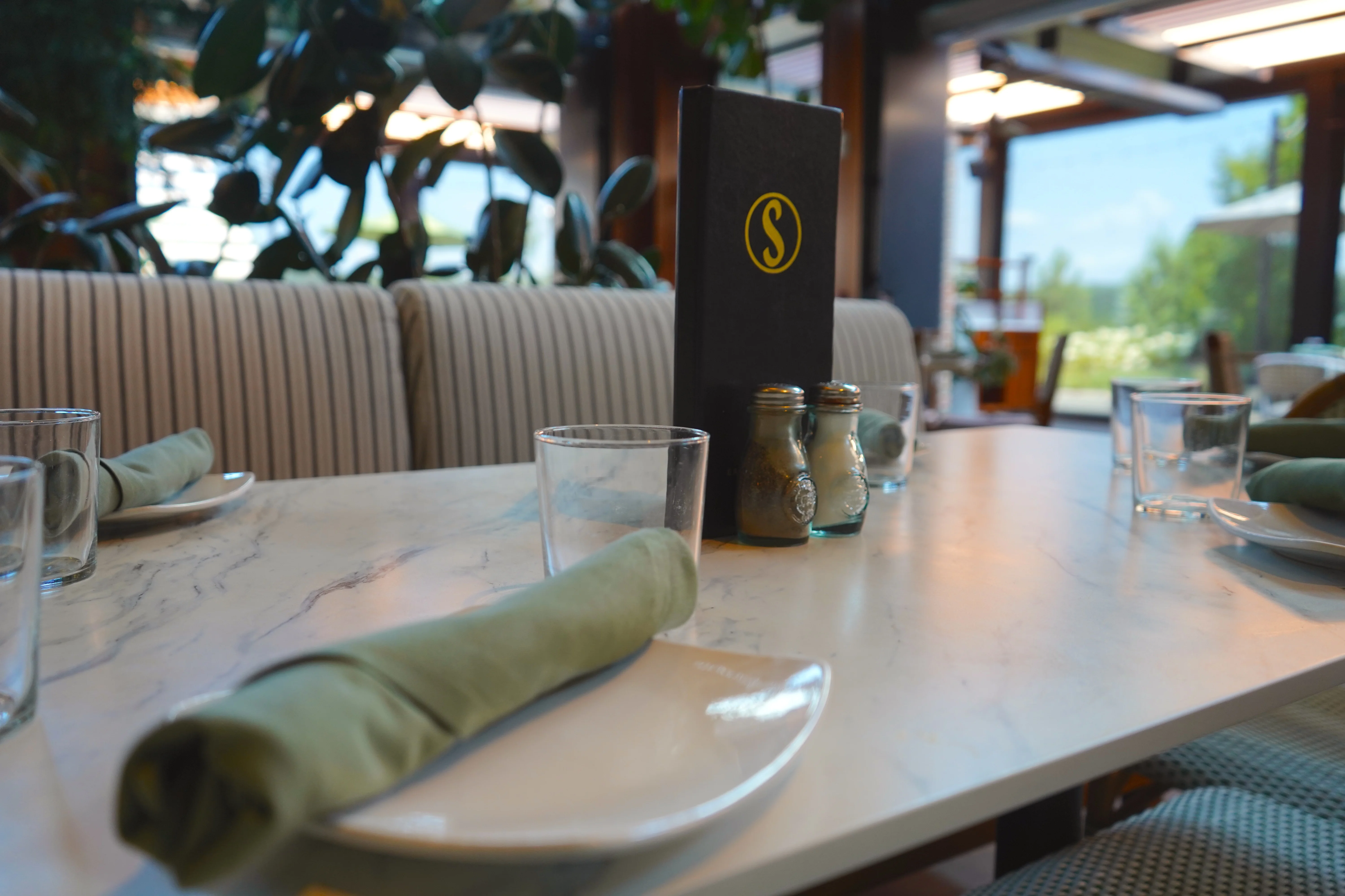 Elegant restaurant table setting with menu and greenery
