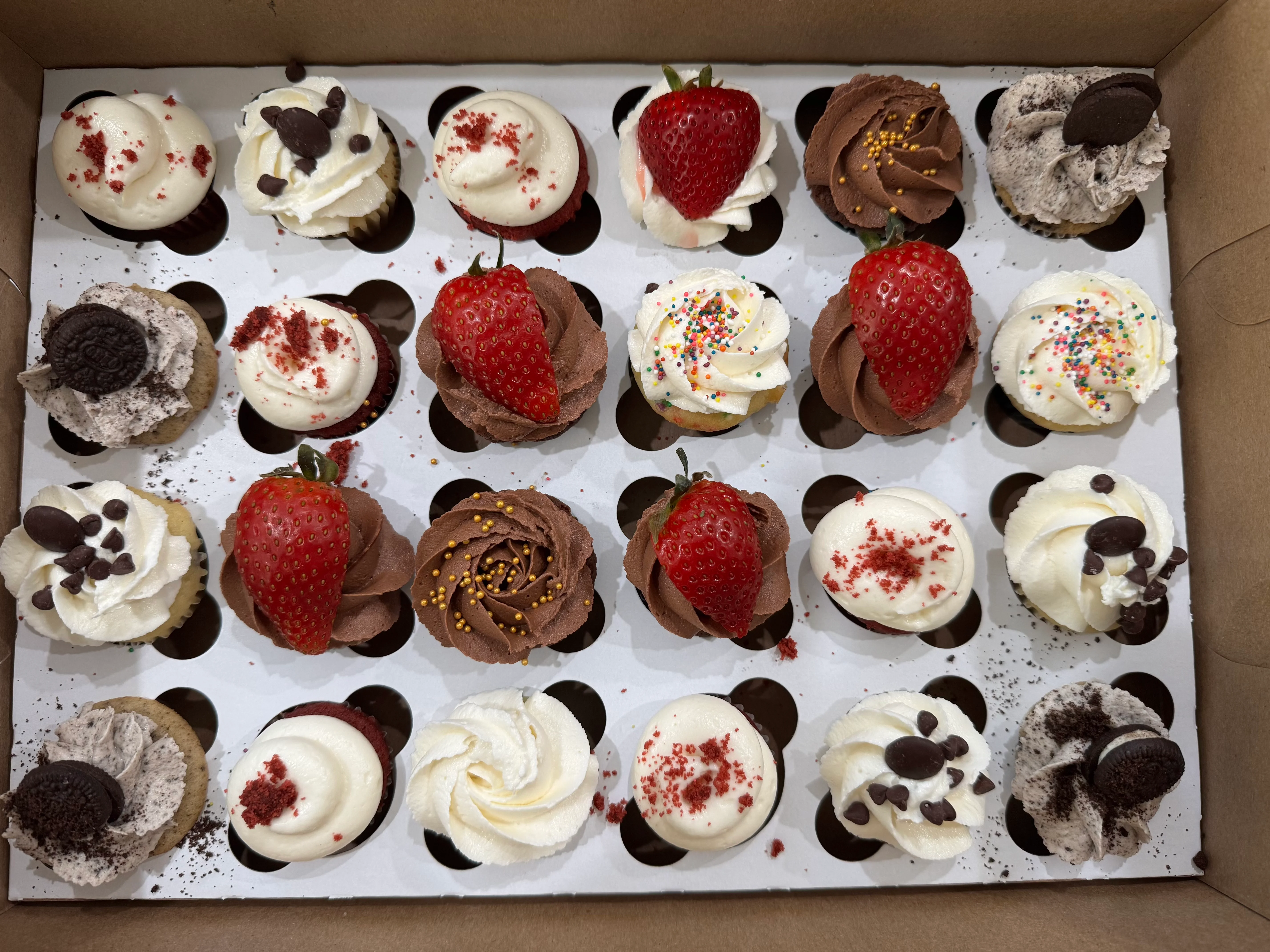 Assorted mini cupcakes in a bakery box