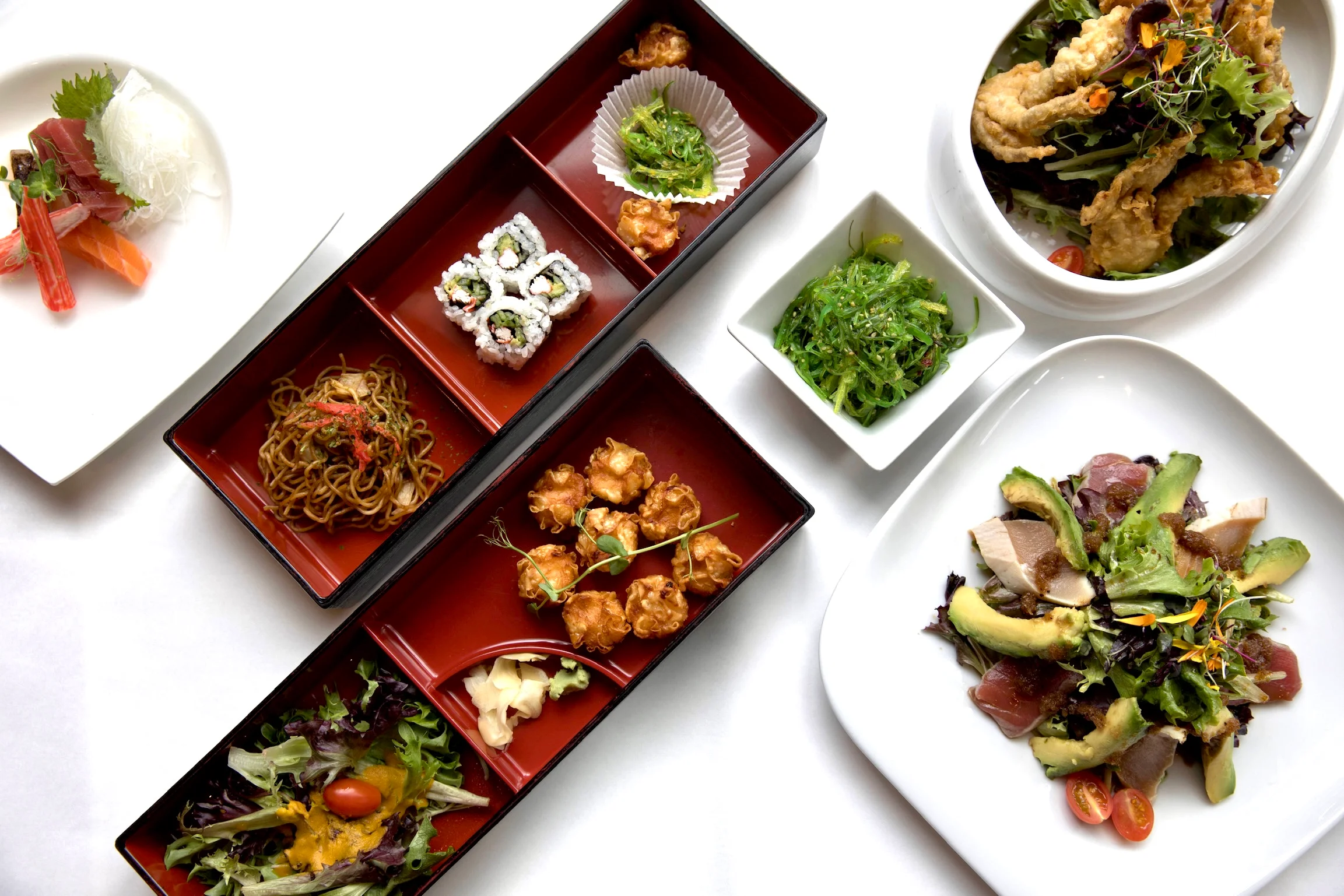 Japanese bento box with sushi, noodles, and salad