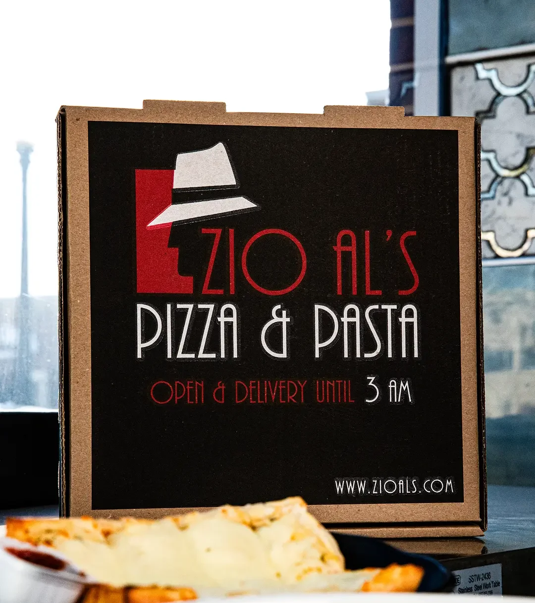 Zio Al's Pizza & Pasta delivery box with food items on a table.