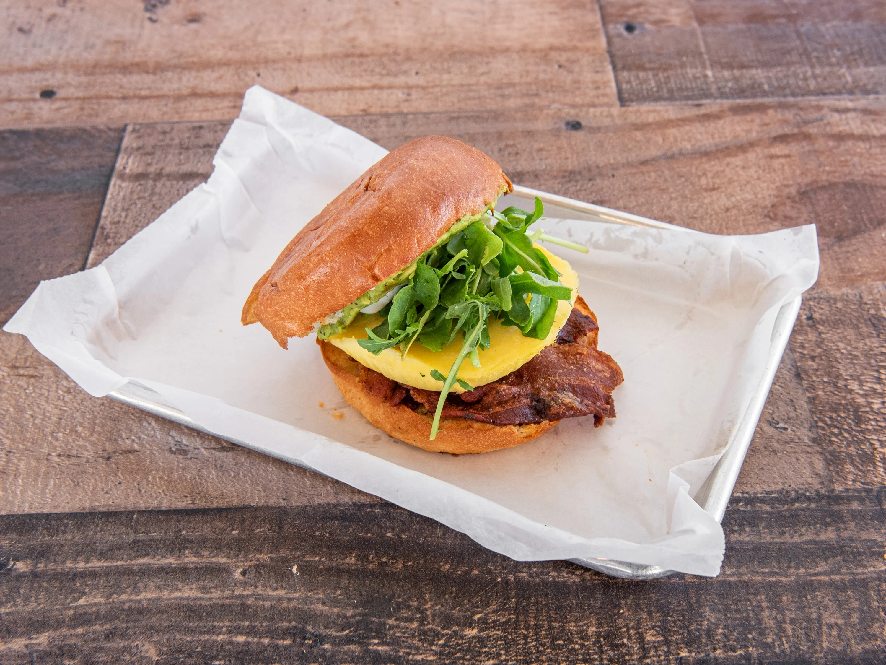 Savory breakfast sandwich with bacon and arugula on a toasted bun