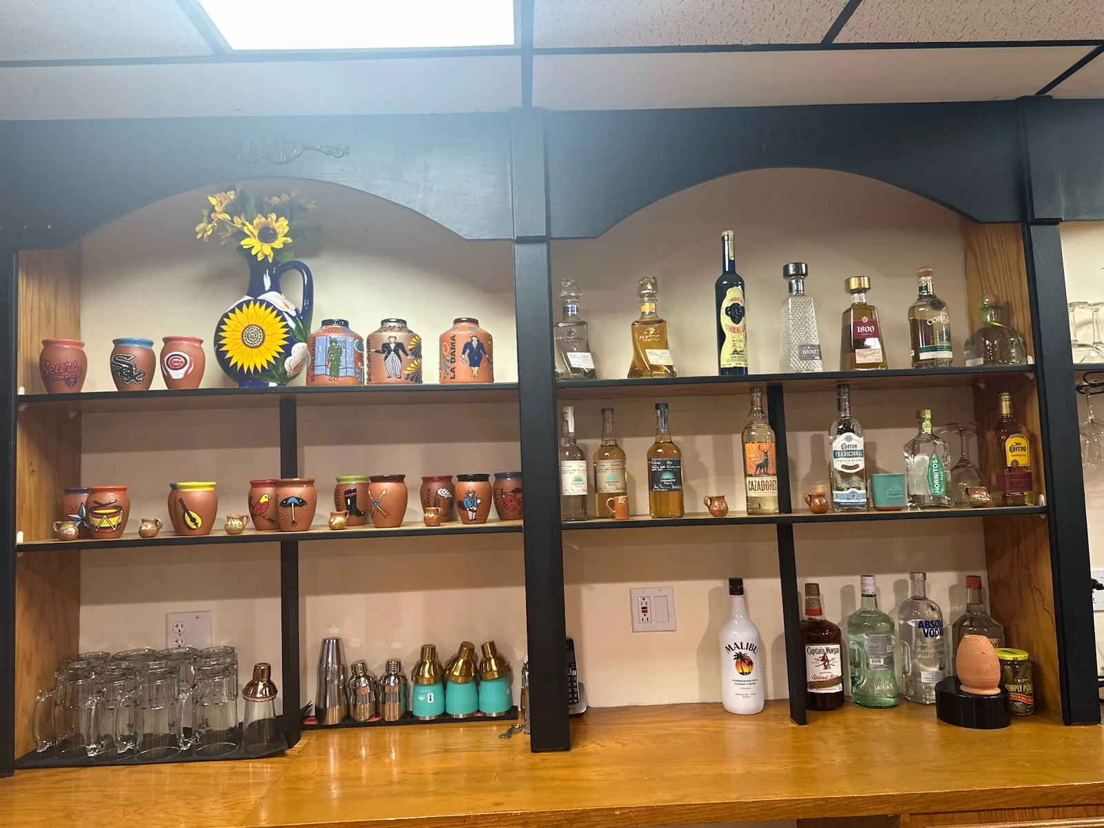 Colorful bar shelf with decorative pottery and assorted spirits