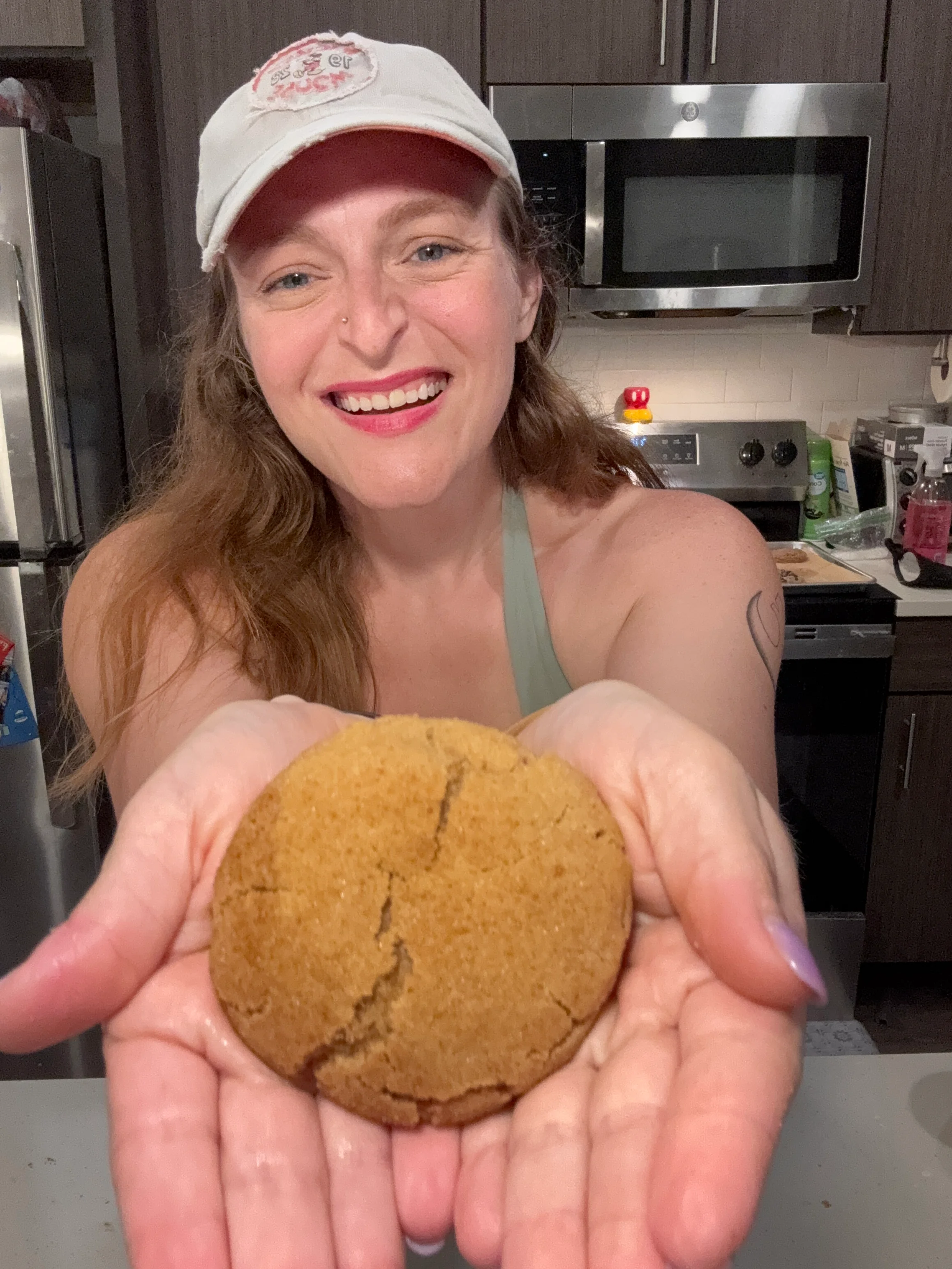 Freshly baked ginger cookie held by a smiling person