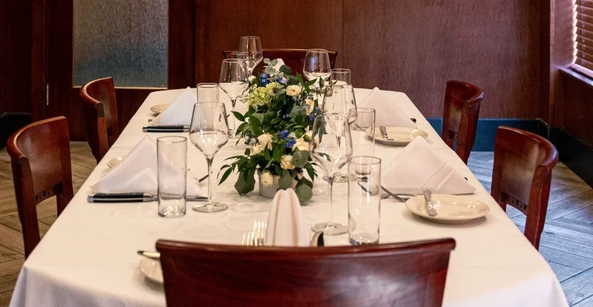 The Obsidian Room private dining space at Bass Street in Moline, IL — seats up to 24 guests with a long table, wood paneling, and dark wallpaper