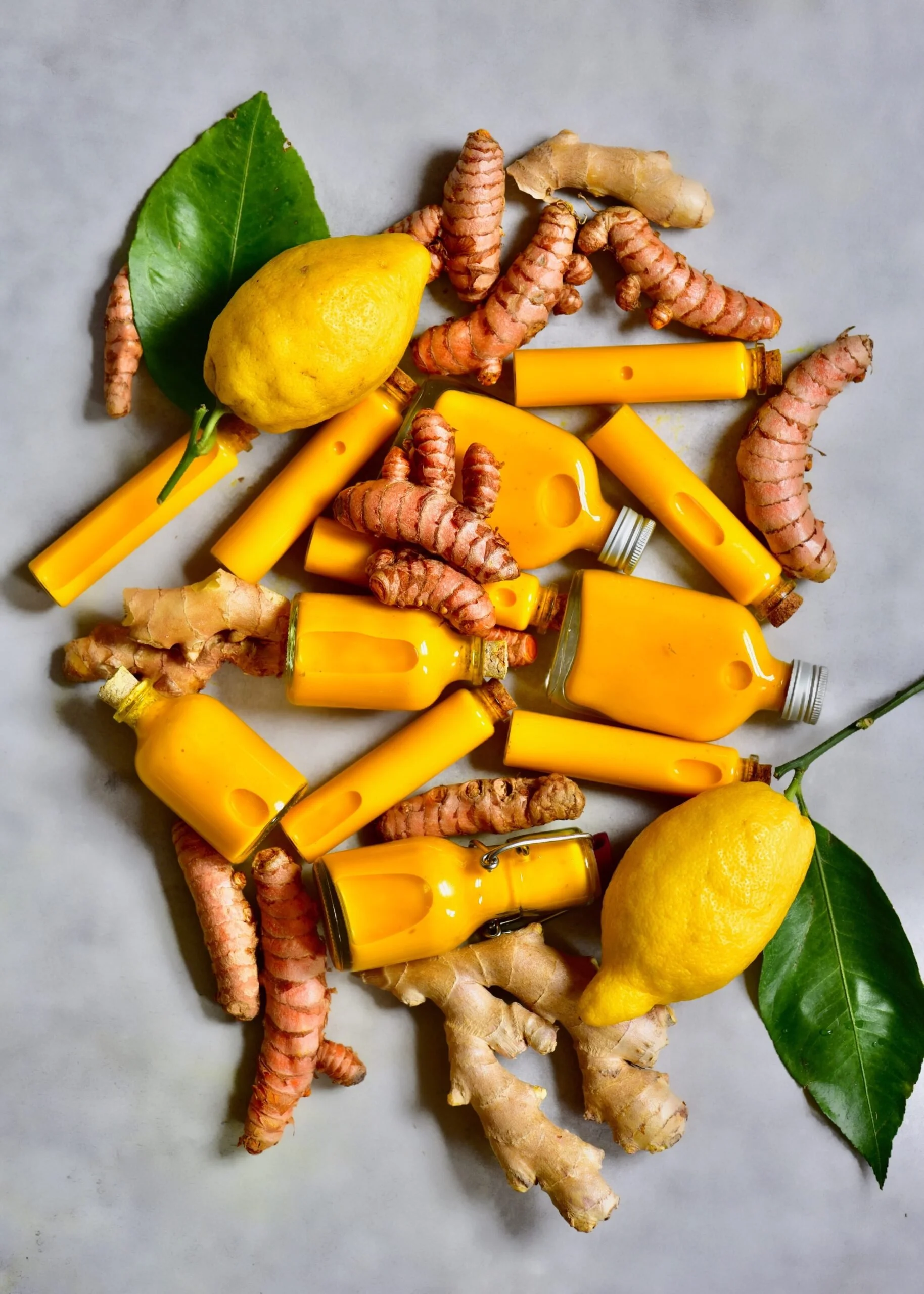 Turmeric and ginger roots with fresh lemons and vibrant bottles