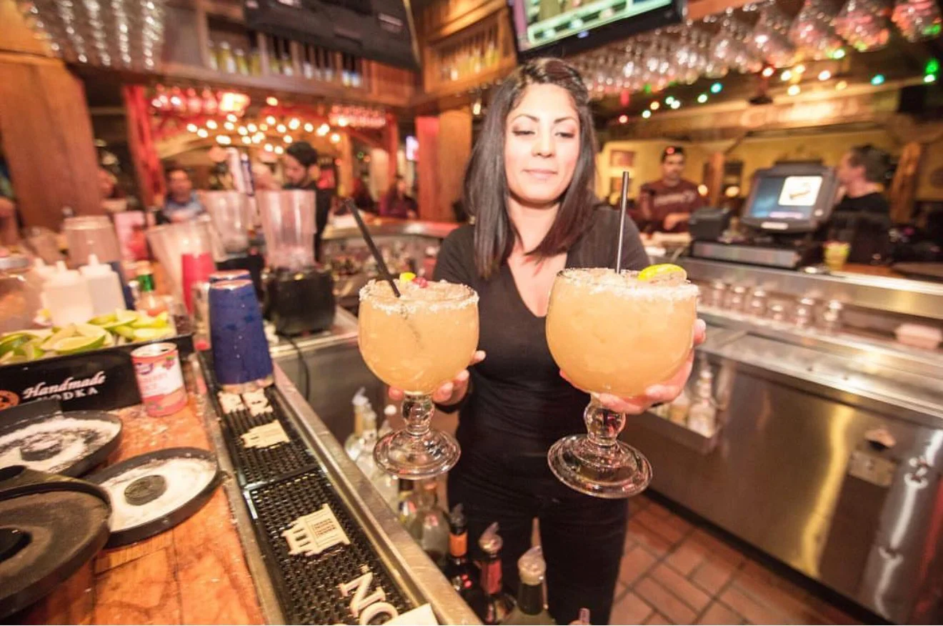 Bartender serving vibrant cocktails at a lively bar