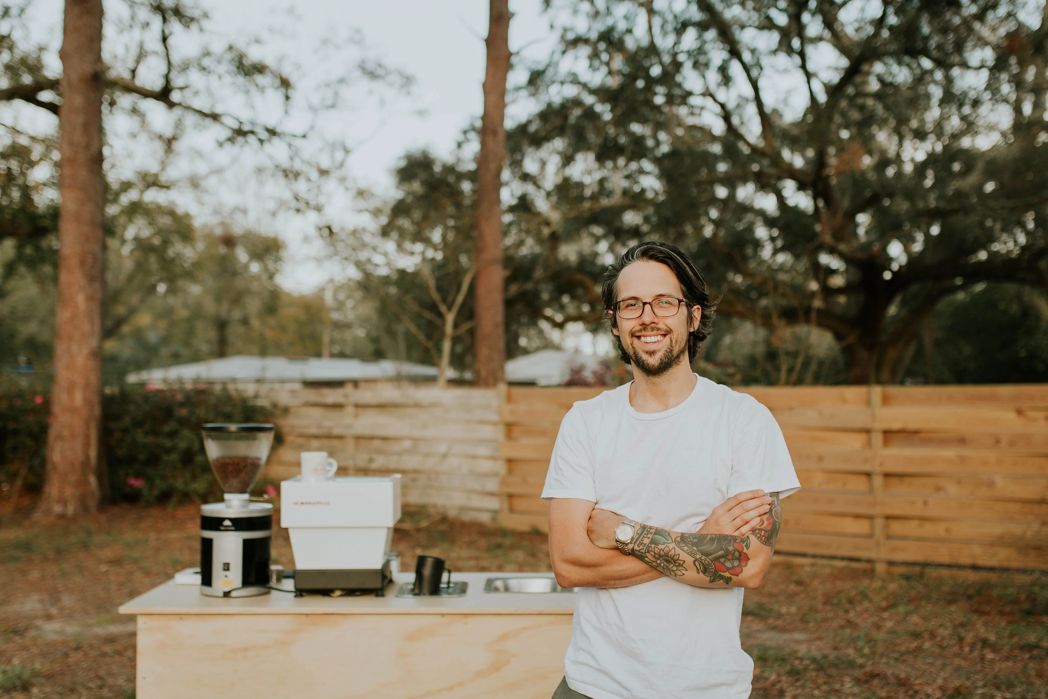 Barista smiling in outdoor coffee setup with brewing equipment