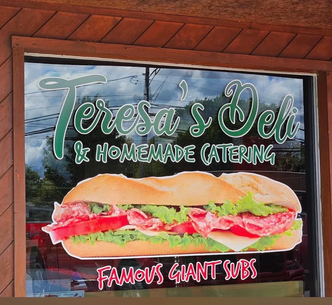 Deli sign featuring giant subs and homemade catering