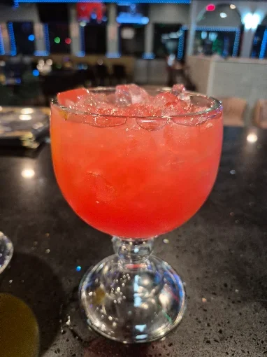 Vibrant cocktail in a glass with ice at a modern bar