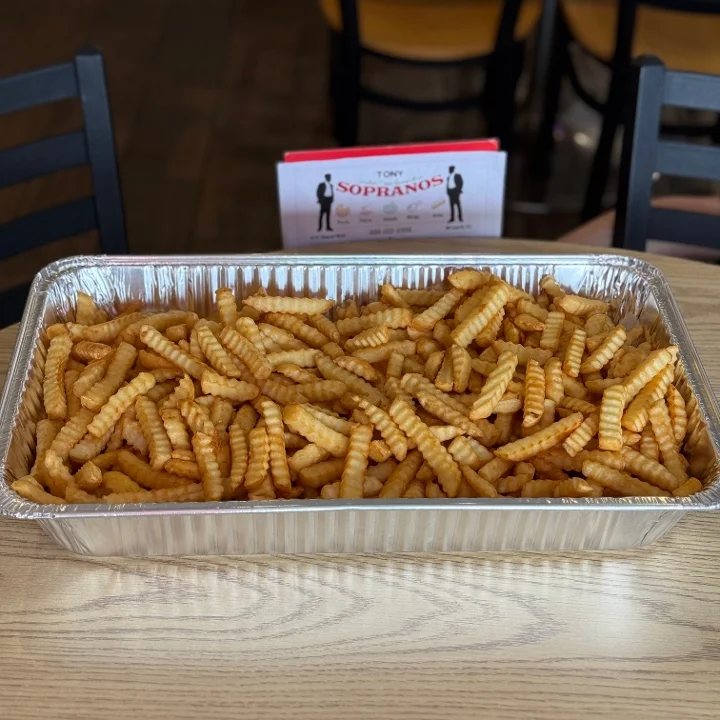 A large aluminum tray filled with golden, crinkly French fries arranged neatly.