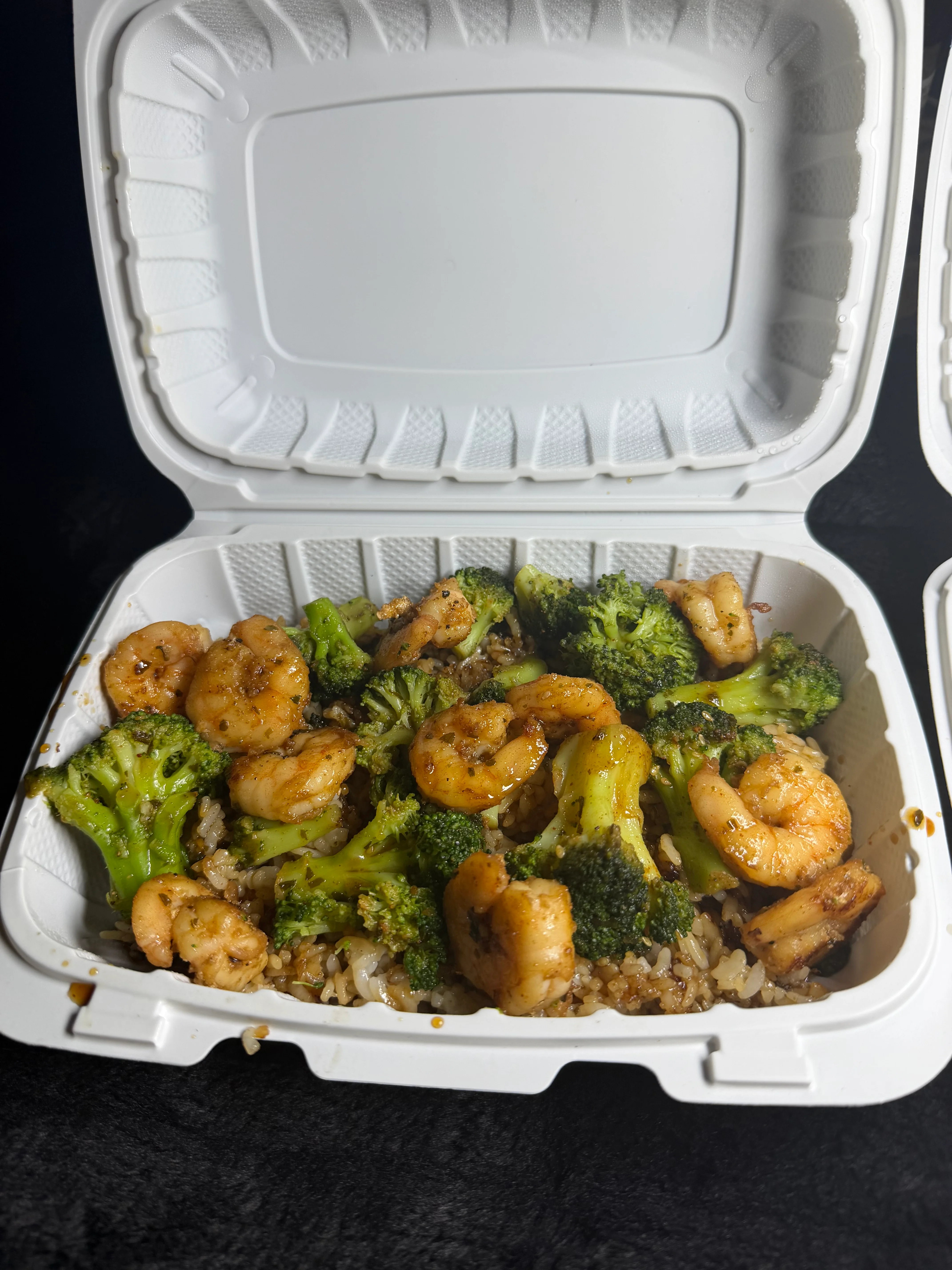 Shrimp and broccoli stir-fry with rice in a takeout container