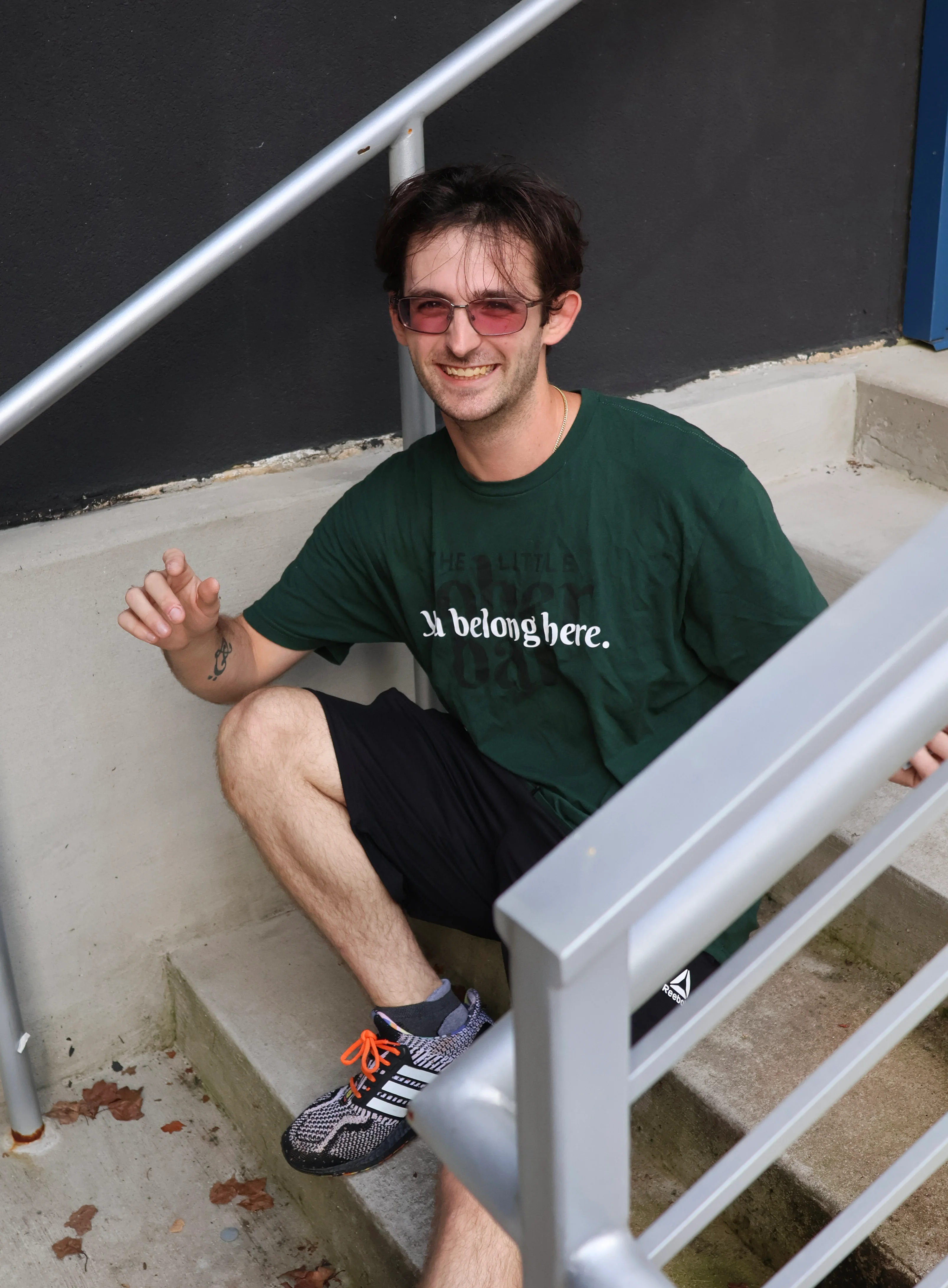 Person holding a rainbow flag beside outdoor concrete steps